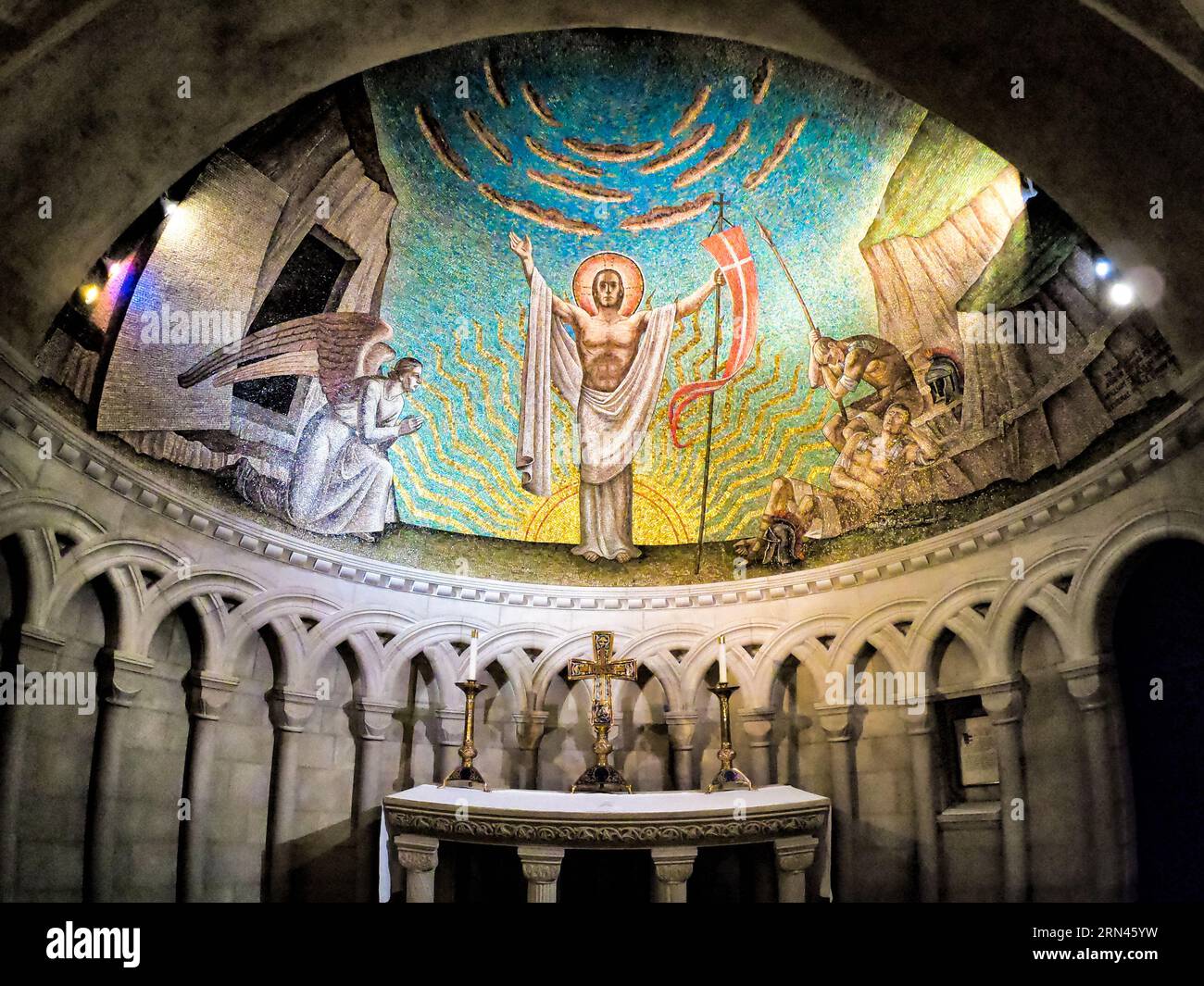 WASHINGTON, DC, USA – Ein detailgetreues Mosaik, das die Auferstehung Jesu Christi darstellt, ziert die halbkuppelte Decke über dem Altar in der Auferstehungskapelle der National Cathedral in Washington, DC. Die Kapelle wurde im normannischen Stil erbaut und verfügt über intime Räume mit Halbkreisbögen und unteren Decken. Dieses von der Künstlerin Hildreth Meirère geschaffene Mosaik ist Teil einer Serie, die Jesu’ Erscheinungen nach der Auferstehung illustriert, mit zusätzlichen Mosaiken, die Rowan und Irene LeCompte an den Seitenwänden entwerfen. Stockfoto