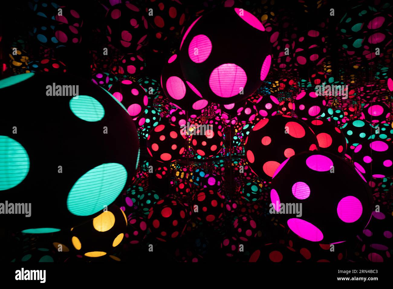 Yayoi Kusama Infinity Room Hirshhorn Museum Washington DC | WASHINGTON D.C., Vereinigte Staaten – Spiegelkugeln mit Punktmuster leuchten in einem der Infinity-Räume von Yayoi Kusama im Smithsonian Hirshhorn Museum. Als Teil der Ausstellung „One with Eternity“ verwendet die Installation Spiegel und wiederholte gepunktete Formen, um eine Illusion von endlosem Raum zu schaffen, eine Technik, die der japanische Künstler seit den 1960er Jahren entwickelt hat Stockfoto