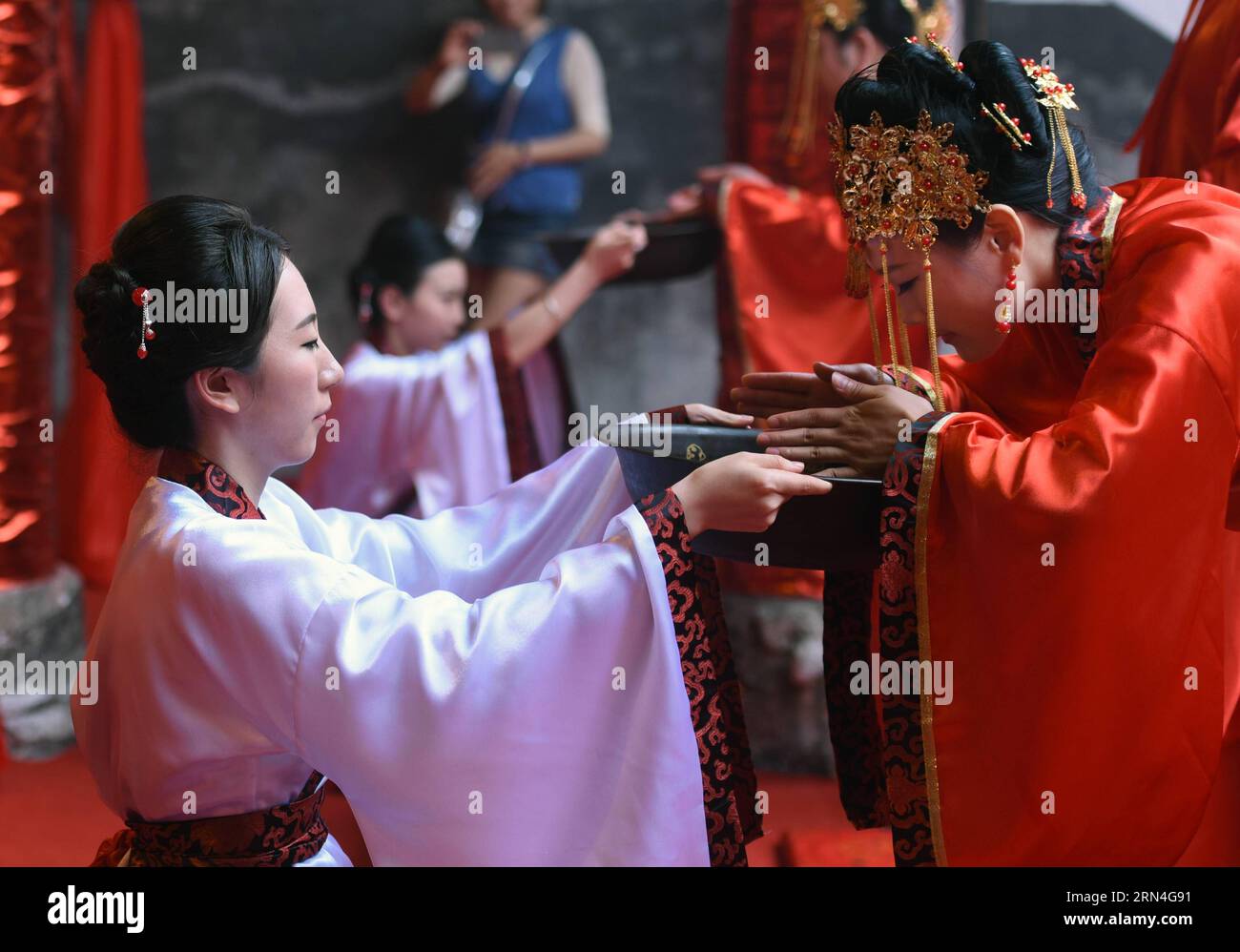 (150520) -- RUCHENG, 20. Mai 2015 -- Dienerinnen im weißen Kleid dienen den Bräuten während einer gemeinsamen traditionellen Han-Hochzeit in einer Vorfahrthalle in Rucheng, Provinz Hunan in Zentralchina, 20. Mai 2015. Der 20. Mai wird in chinesischer Sprache ähnlich wie wo ai Ni ausgesprochen, was „Ich liebe dich“ bedeutet, und am Mittwoch fand eine traditionelle Gruppenhochzeit für 10 Paare im Ahnensaal in Rucheng statt. Die Ahnensaal ist ein chinesischer Tempel, der vergöttlichten Ahnen und Vorfahren von Familiennamen oder Familien in der chinesischen Kultur gewidmet ist. Und heute ist der Stammsaal in Rucheng zum Prominenten geworden Stockfoto