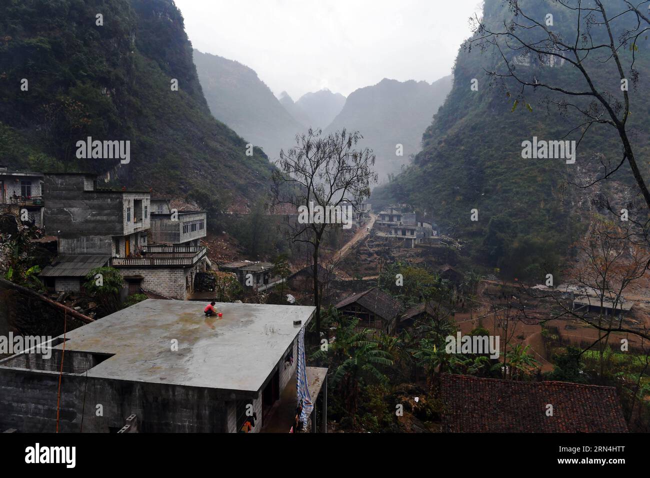 Lan Xiuxiang sammelt Regenwasser auf dem Dach ihres Hauses im Dorf Nongyong der Gemeinde Bansheng im Autonomen Kreis Dahua Yao, südwestchinesische autonome Region Guangxi Zhuang, 12. Februar 2015. Die Bansheng Township liegt im Zentrum der Karst-Landformen im Westen von Guangxi und leidet seit Ewigkeiten unter einem starken Wassermangel. Die Niederschläge sind daher ein Segen für die Menschen, die seit etwa 1.000 Jahren auf diesem Land leben und hauptsächlich der ethnischen Gruppe der Yao angehören. Um ihren täglichen Lebensbedürfnissen gerecht zu werden, sammeln die Einheimischen immer Regenwasser mit Eimern und Fässern jeder Größe sowie mit Dächern ihrer Häuser. In t Stockfoto