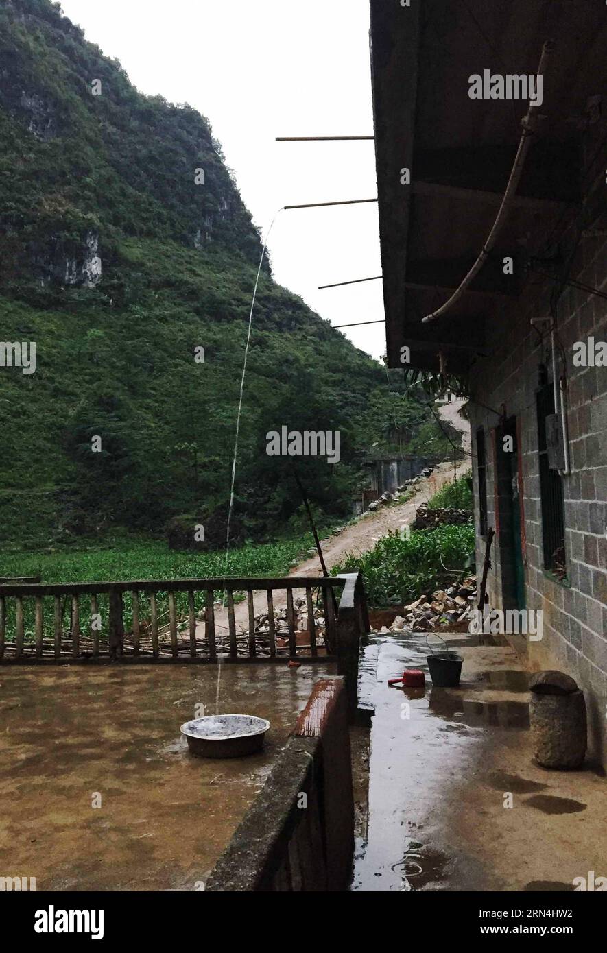 Regenwasser wird auf dem Dach eines Hauses im Dorf Nongyong der Gemeinde Bansheng im Autonomen Komitat Dahua Yao im Südwesten Chinas Guangxi Zhuang am 15. Mai 2015 gesammelt. Die Bansheng Township liegt im Zentrum der Karst-Landformen im Westen von Guangxi und leidet seit Ewigkeiten unter einem starken Wassermangel. Die Niederschläge sind daher ein Segen für die Menschen, die seit etwa 1.000 Jahren auf diesem Land leben und hauptsächlich der ethnischen Gruppe der Yao angehören. Um ihren täglichen Lebensbedürfnissen gerecht zu werden, sammeln die Einheimischen immer Regenwasser mit Eimern und Fässern jeder Größe sowie mit Dächern ihrer Häuser. In der Vergangenheit Deca Stockfoto