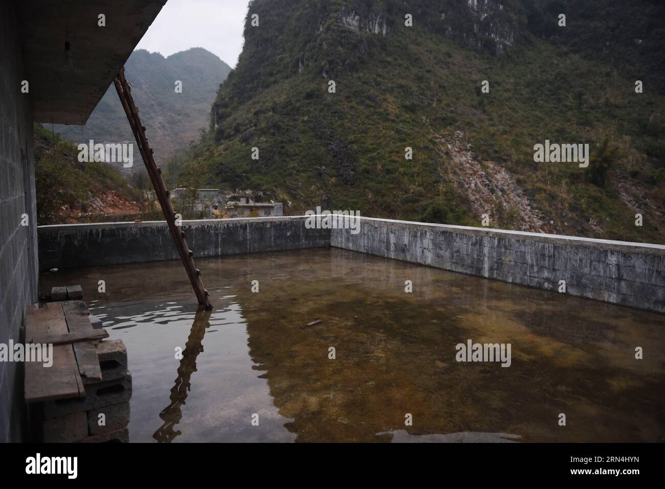 Regenwasser wird auf dem Dach eines Hauses im Dorf Nongyong der Gemeinde Bansheng im Autonomen Komitat Dahua Yao im Südwesten Chinas Guangxi Zhuang am 17. Februar 2015 gesammelt. Die Bansheng Township liegt im Zentrum der Karst-Landformen im Westen von Guangxi und leidet seit Ewigkeiten unter einem starken Wassermangel. Die Niederschläge sind daher ein Segen für die Menschen, die seit etwa 1.000 Jahren auf diesem Land leben und hauptsächlich der ethnischen Gruppe der Yao angehören. Um ihren täglichen Lebensbedürfnissen gerecht zu werden, sammeln die Einheimischen immer Regenwasser mit Eimern und Fässern jeder Größe sowie mit Dächern ihrer Häuser. Im vergangenen dez. Stockfoto