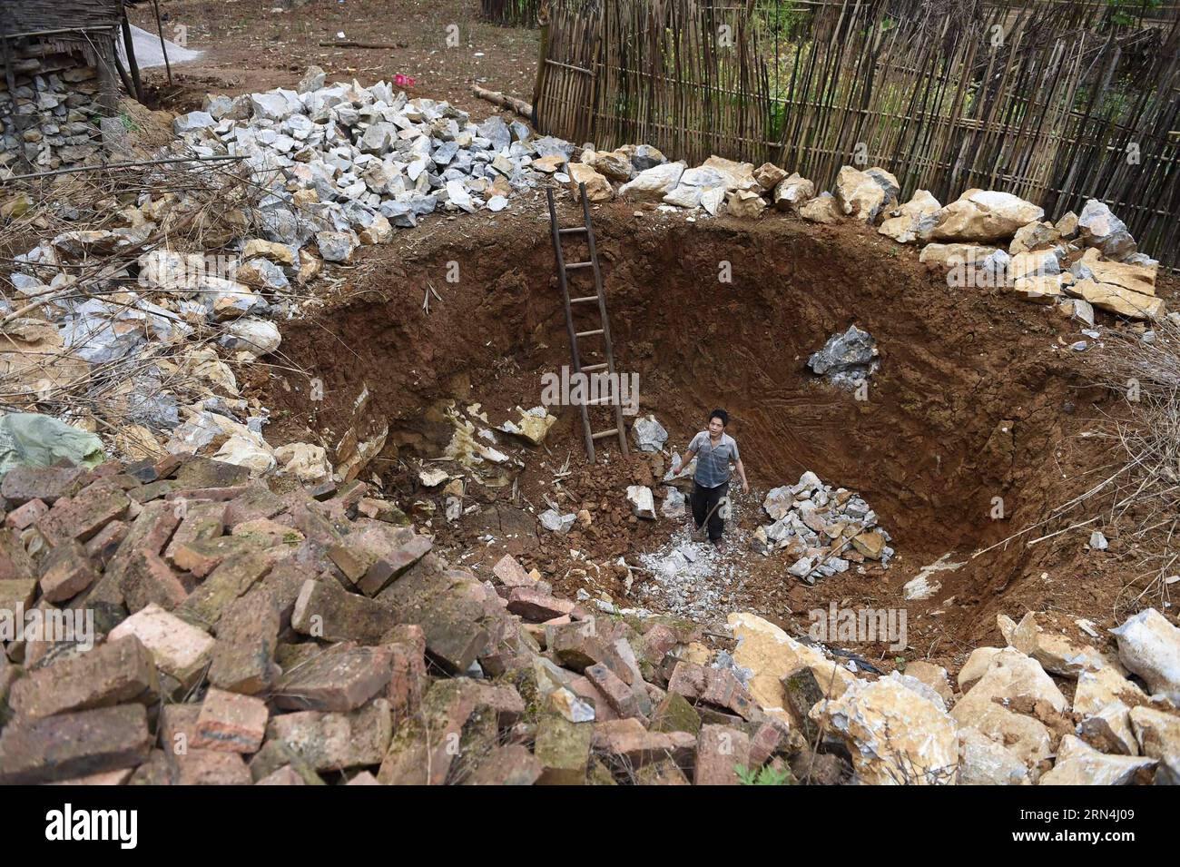 Lan Yude, 47, baut einen Wassertank im Dorf Nongyong in der Gemeinde Bansheng im Autonomen Kreis Dahua Yao im Südwesten Chinas Guangxi Zhuang, 25. Februar 2015. Die Bansheng Township liegt im Zentrum der Karst-Landformen im Westen von Guangxi und leidet seit Ewigkeiten unter einem starken Wassermangel. Die Niederschläge sind daher ein Segen für die Menschen, die seit etwa 1.000 Jahren auf diesem Land leben und hauptsächlich der ethnischen Gruppe der Yao angehören. Um ihren täglichen Lebensbedürfnissen gerecht zu werden, sammeln die Einheimischen immer Regenwasser mit Eimern und Fässern jeder Größe sowie mit Dächern ihrer Häuser. In den letzten zehn Jahren wurde der Standort Stockfoto