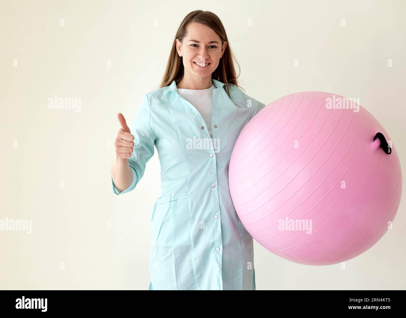 Smiley Physiotherapeut hält den Übungsball und gibt den Daumen nach oben Stockfoto