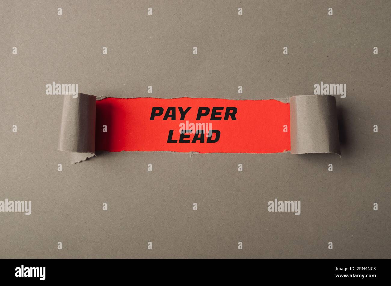 Der Text „Pay per Lead“ ist durch ein Loch in grauem Papier sichtbar Stockfoto