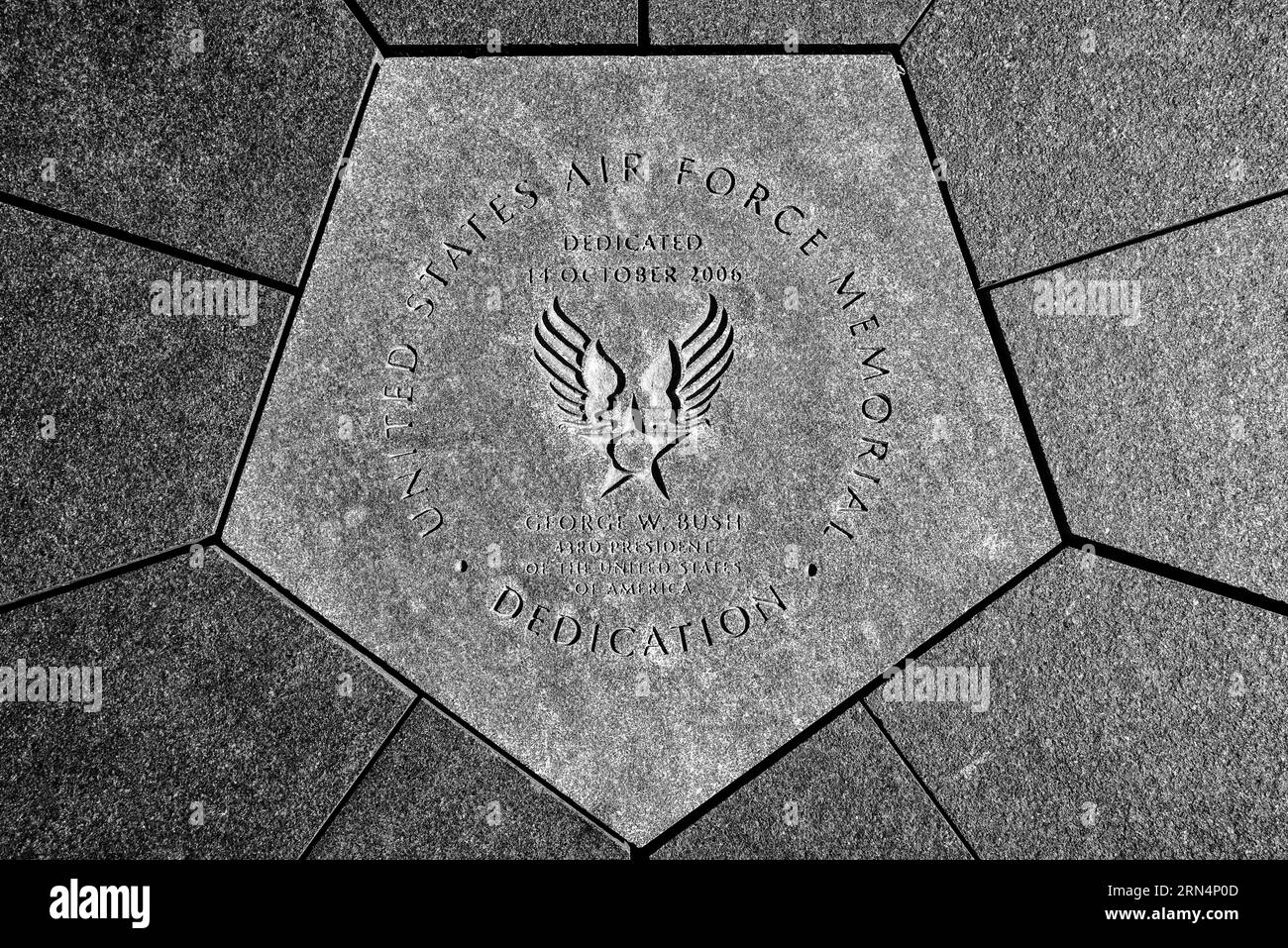 Widmungsstein, US Air Force Memorial, Arlington. Schwarz-weiß-Foto mit dem fünfeckigen Stein mit eingraviertem Text und dem Air Force Symbol umgeben von Pflastersteinen. Stockfoto