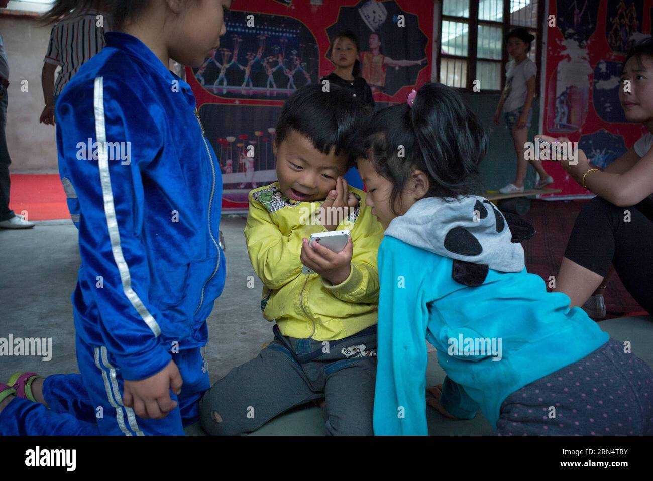 (150531) -- HEFEI, 31. Mai 2015 -- Foto aufgenommen am 26. Mai 2015 zeigt Kinder, die nach Akrobatikübungen in einer Akrobatik-Schule im Dorf Sanwang im Bezirk Yingshang in der ostchinesischen Provinz Anhui Spiele auf einem Handy spielen. Die 2007 gegründete Akrobatik-Schule im Dorf Sanwang schreibt jedes Jahr mehr als hundert Kinder ein, die Akrobatik lernen, um ihren Lebensunterhalt zu verdienen. ) (Zwx) CHINA-ANHUI-YINGSHANG-CHILDREN-ACROBATICS(CN) GuoxChen PUBLICATIONxNOTxINxCHN 150531 Hefei Mai 31 2015 Foto aufgenommen AM 26 2015. Mai zeigt Kinder, die nach Akrobatikübungen Spiele AUF einem Handy spielen i Stockfoto