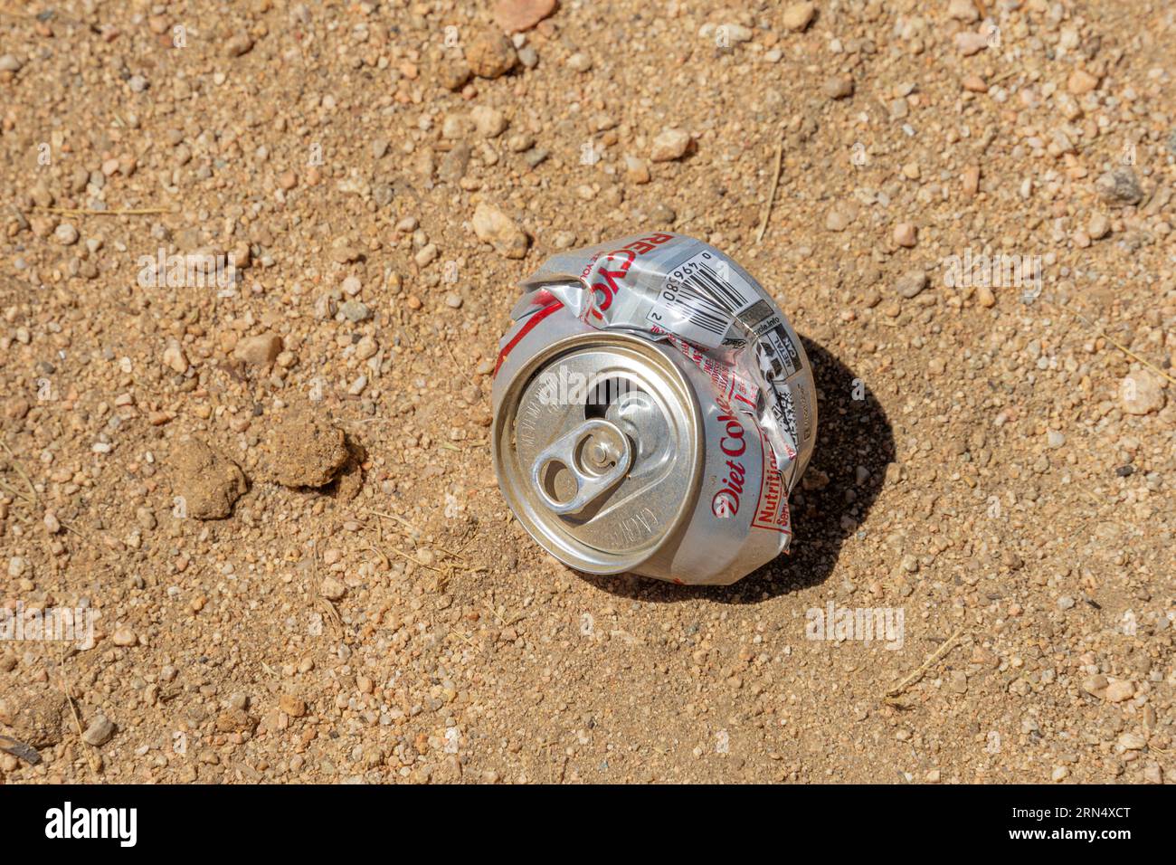 Victorville, CA, USA - 27. Juli 2023: Ein zerstoßenes Alu-Soda kann auf einem sandigen Untergrund in der Mojave-Wüste zurückbleiben. Stockfoto