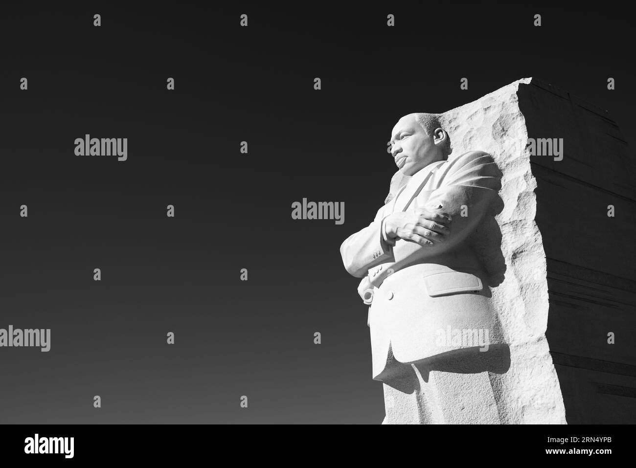 Martin Luther King Jr. Memorial Statue, Washington, D.C. Schwarzweißfoto, das die geschnitzte Steinfigur mit überkreuzten Armen aus einem niedrigen Winkel zeigt. Stockfoto
