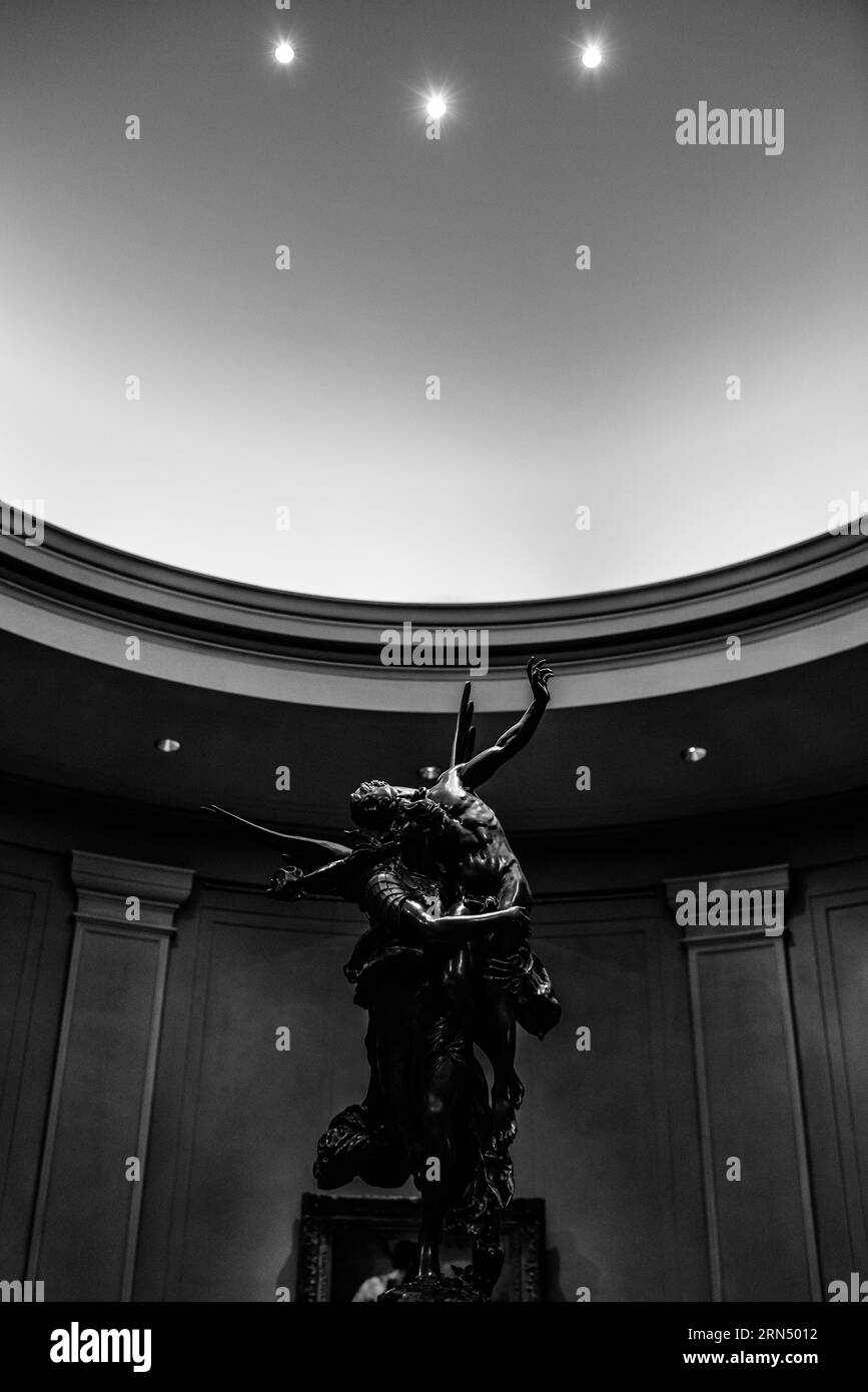 Gloria Victis Skulptur, National Gallery of Art, Washington, D.C. Schwarzweiß-Fotografie zeigt einen niedrigen Winkel der Bronzeskulptur vor einem Hintergrund von architektonischen Details und Deckenleuchten. Stockfoto