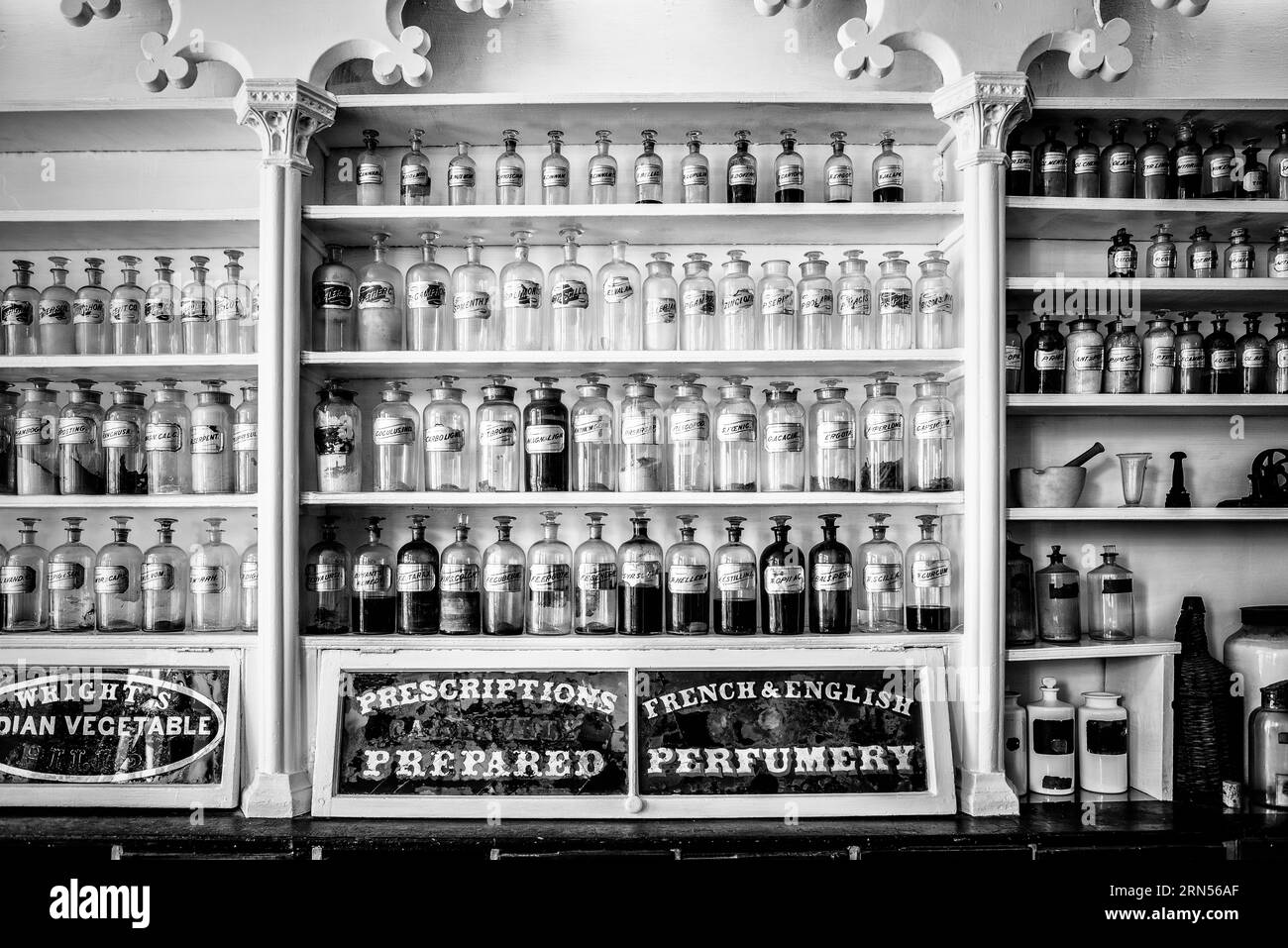 Antike Arzneiflaschen, Stabler-Leadbeater Apothekenmuseum, Alexandria. Schwarzweiß-Foto mit Regalen, die mit gekennzeichneten Glasflaschen und pharmazeutischen Geräten gefüllt sind. Stockfoto