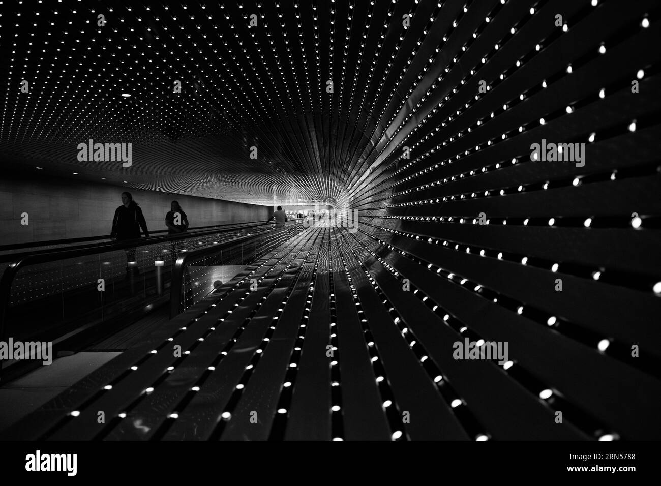 „Multiverse“-Lichtskulptur, National Gallery of Art, Washington, D.C. Schwarzweißfoto, das den Tunnel der Lichter und Menschen auf der Rolltreppe zeigt. Stockfoto