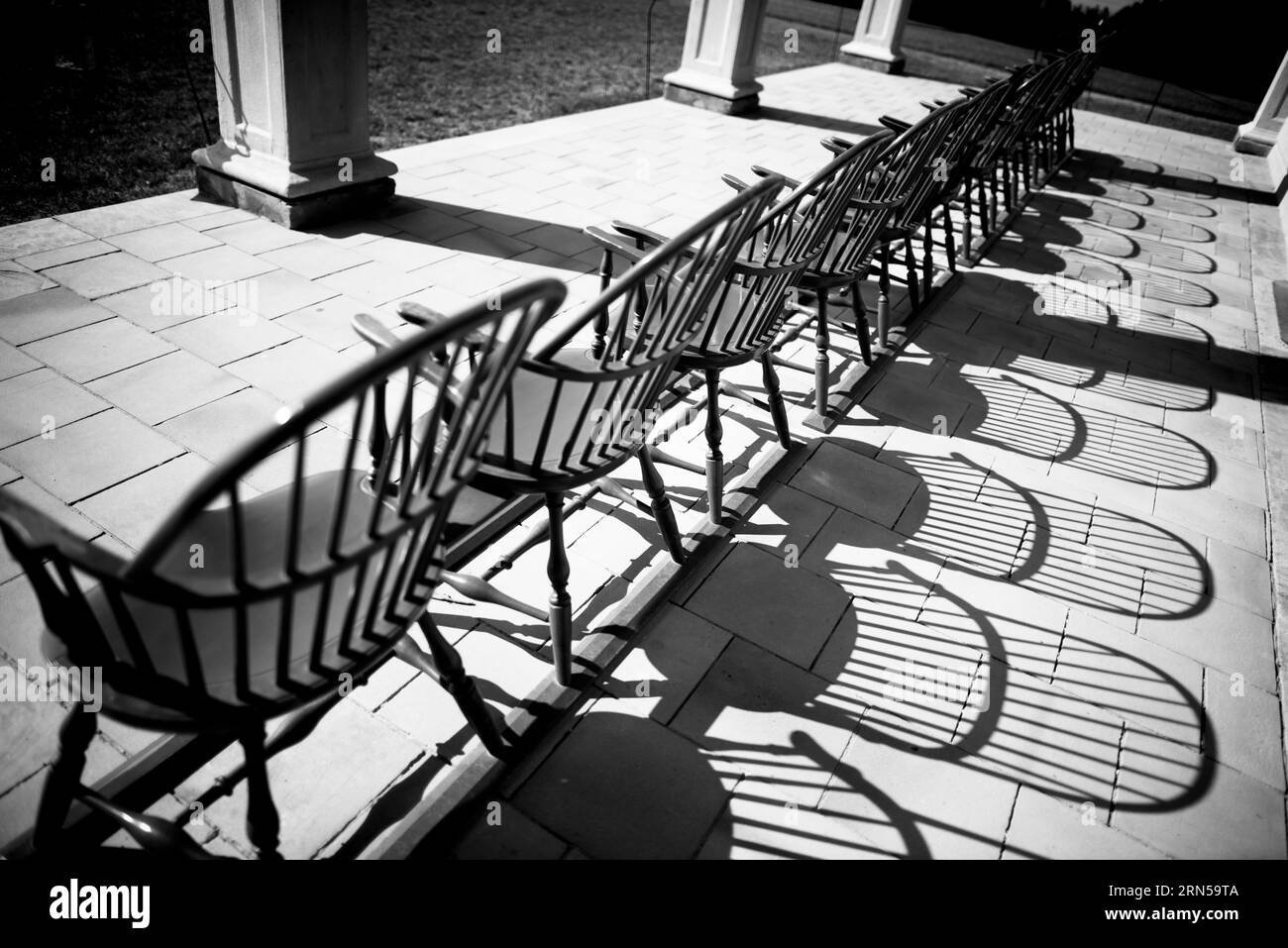 Windsor Stühle, Mount Vernon, Alexandria. Das Schwarzweiß-Foto zeigt eine Reihe von Stühlen und deren Schatten auf einer steinplatte. Stockfoto