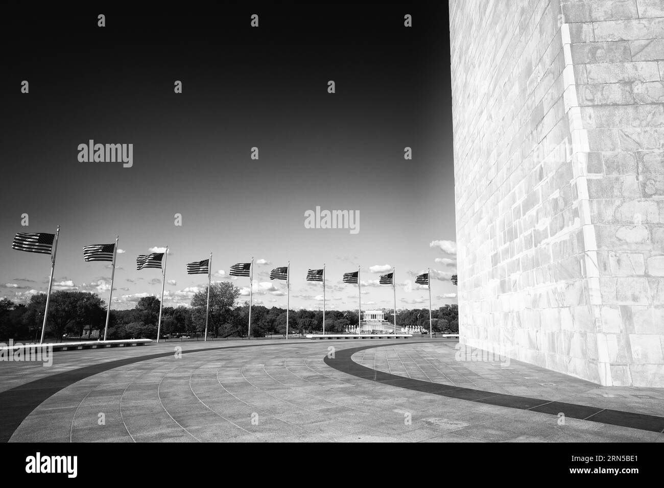 Amerikanische Flaggen und das Washington Monument, Washington, D.C. Schwarzweiß-Foto, das eine Reihe von Flaggen zeigt, die zum Fuß des Monuments führen. Stockfoto