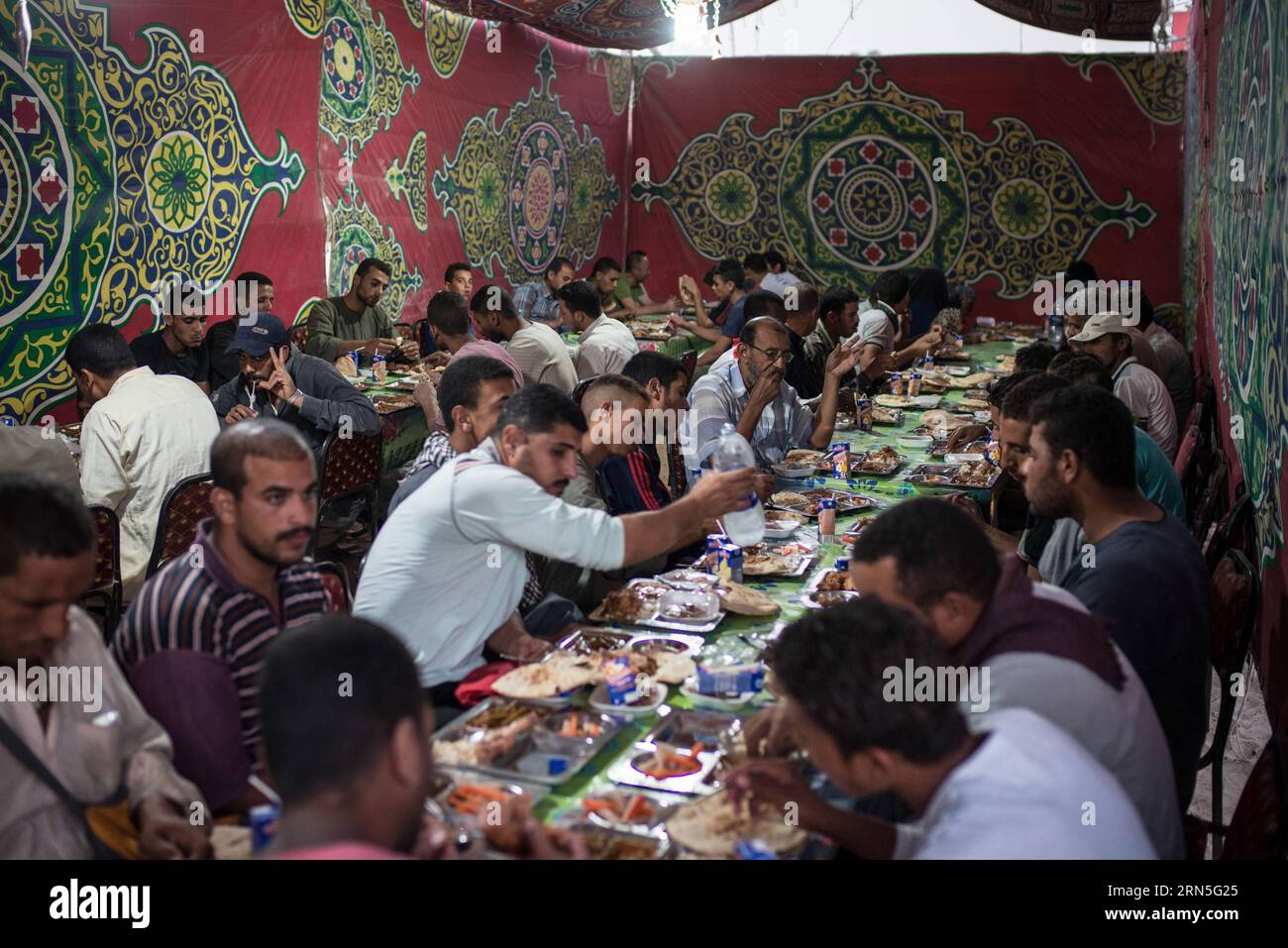 (150625) -- KAIRO, 24. Juni 2015 -- Ägyptische Muslime haben das schnelle Essen Iftar auf einem Benefizbankett, das von chinesischen Firmen in Kairo, Ägypten, am 24. Juni 2015 angeboten wird. Die China in Egypt Stone Material Association (CESMA) arbeitet mit der Egyptian Society for Integrated Development (ESID) zusammen, um während des heiligen Monats Ramadan Wohltätigkeitsbankette und Essensboxen für die Bewohner anzubieten. CESMA veranstaltet seit 2012 tägliche Wohltätigkeitsbankette in Ramadan. ) (zw) ÄGYPTEN-KAIRO-CHINA-RAMADAN-CHARITY BANKETT PanxChaoyue PUBLICATIONxNOTxINxCHN 150625 Kairo 24. Juni 2015 Ägyptische Muslime haben die Almos Stockfoto