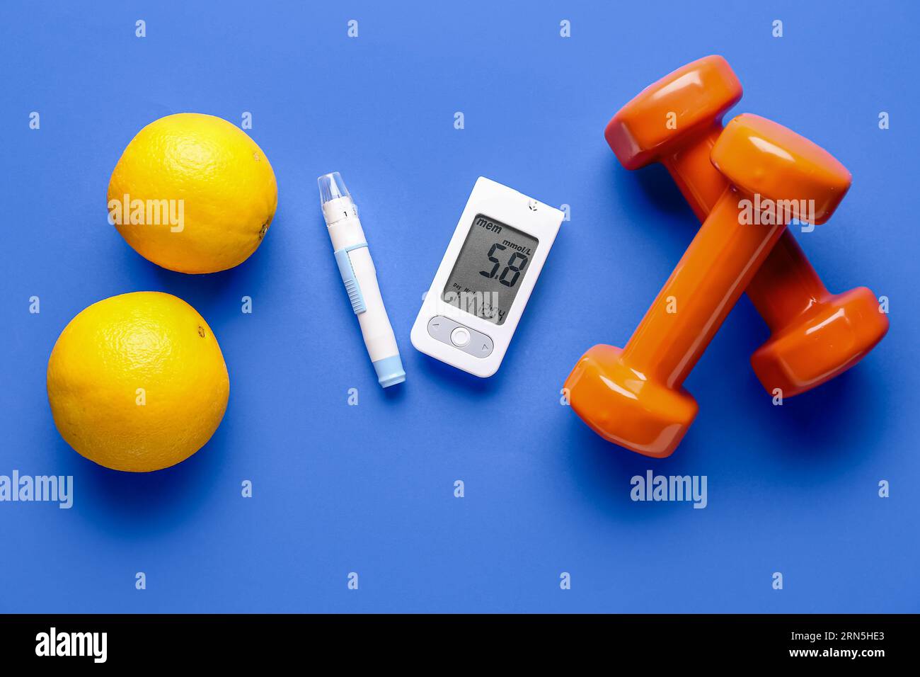 Glucometer, Lanzette, Kurzhanteln und Orangen auf blauem Hintergrund. Diabetes-Konzept Stockfoto