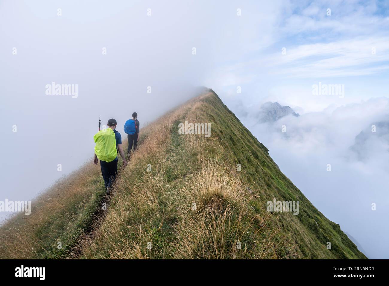 Kletterer auf einem schmalen Hügel, steile grasbedeckte Berge im Nebel, Aufstieg nach Marwes, Saentis, Appenzell Ausserrhoden, Appenzell Alpen, Die Schweiz Stockfoto