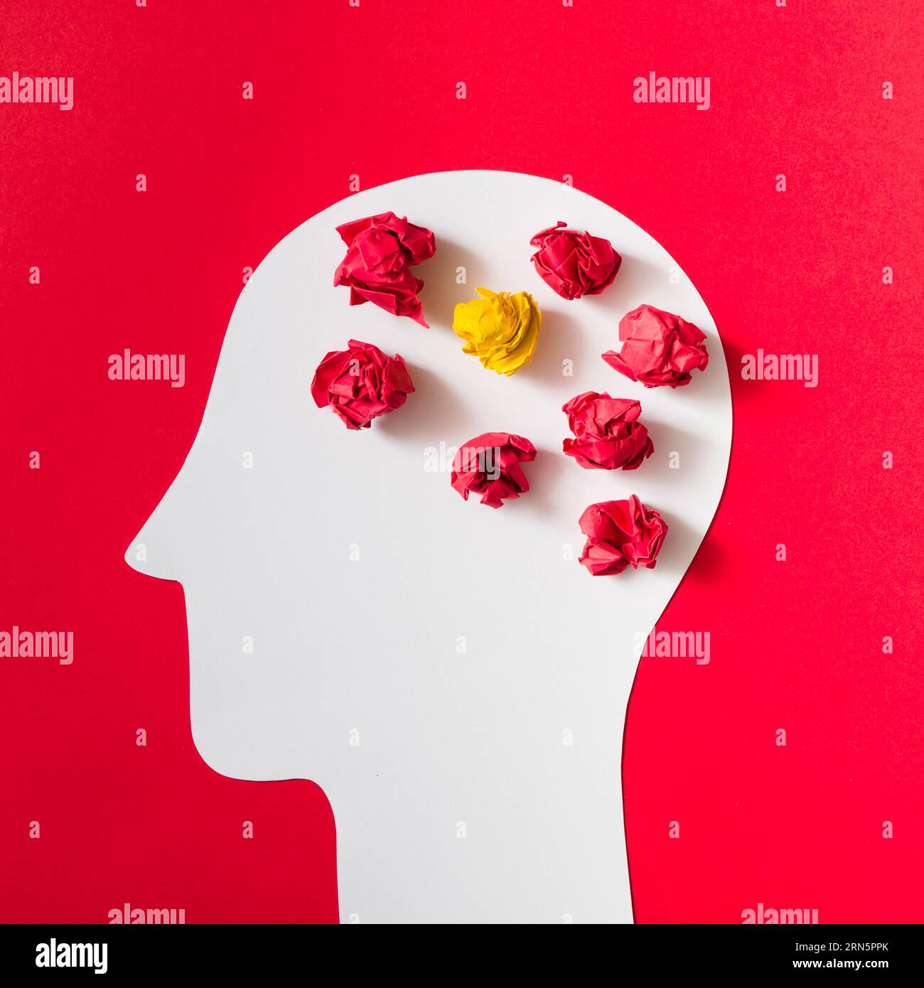 Zerknittertes Papier mit weißem, menschlichem Kopf auf rotem Hintergrund Stockfoto