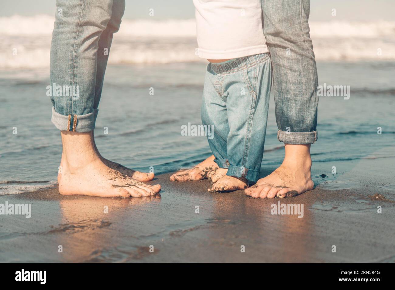Familie steht Sand am Meer Stockfoto