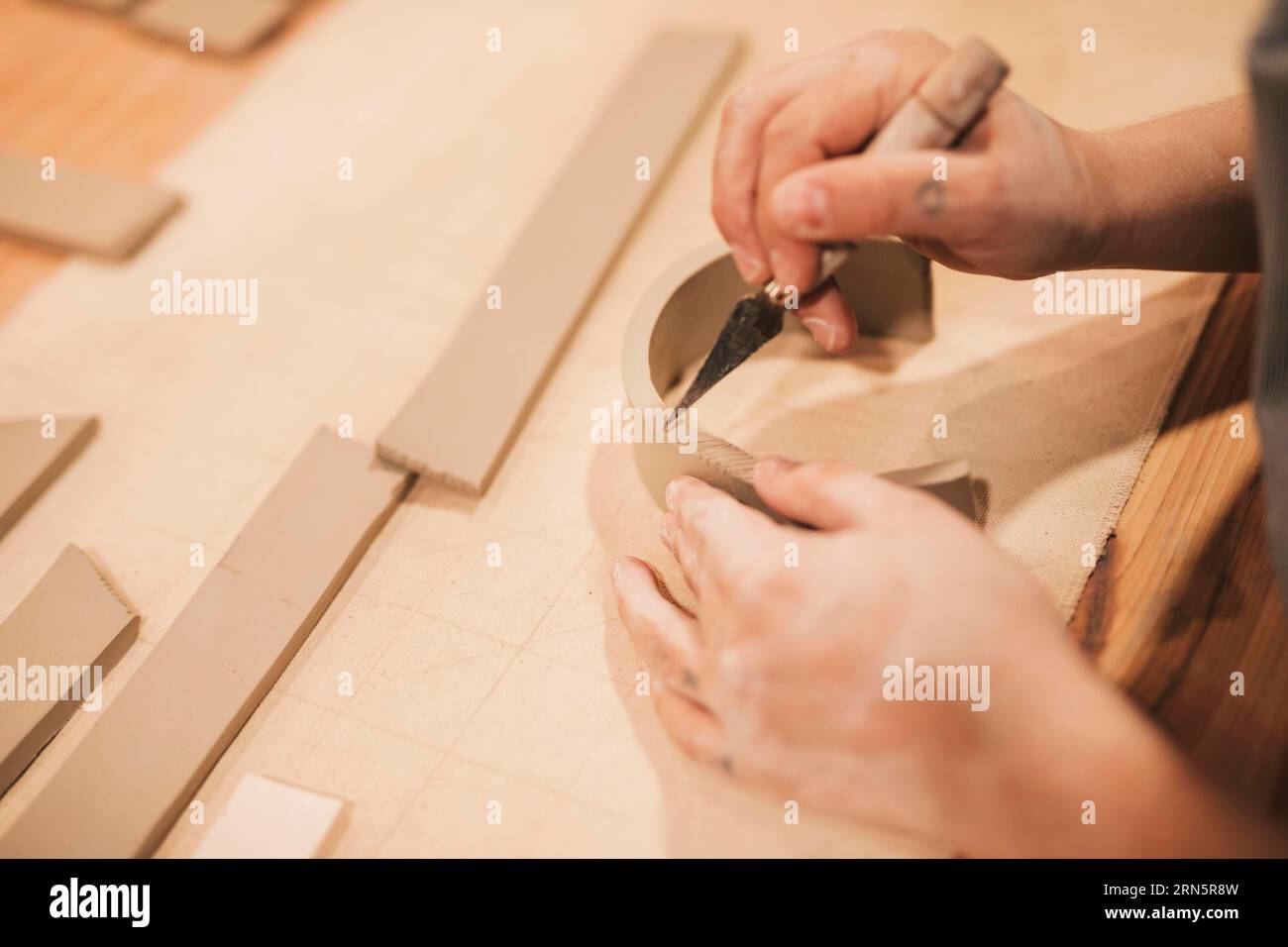 Weibliche Töpferhandgravur Ton mit Werkzeugen Holztisch Stockfoto