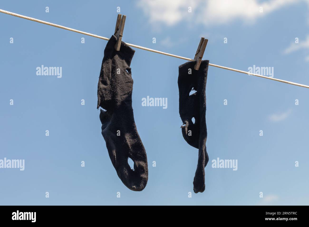 Leckere Socken hängen an der Kleidung am blauen Himmel, ein Konzept, das sich mit Armut beschäftigt Stockfoto
