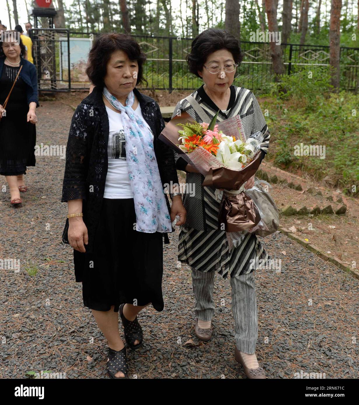 Japanische Bürger, die während des Zweiten Weltkriegs von Chinesen adoptiert wurden, überreichen Blumen auf einem Friedhof, um adoptive chinesische Eltern im Fangzheng County in der Nähe von Harbin, Hauptstadt der nordöstlichen Provinz Heilongjiang, am 13. Juli 2015 zu erinnern. Eine Gruppe von 54 japanischen Staatsbürgern, die alle heute Waisen sind, besuchte am Montag die Gräber ihrer adoptiven chinesischen Eltern hier. Während des voreiligen Rückzugs am Ende des Zweiten Weltkriegs 1945 von ihren Eltern verlassen, wurden die Waisen, die heute über 70 Jahre alt sind, von den sehr chinesischen Bewohnern jener nordöstlichen Provinzen aufgenommen und aufgezogen, die so viel Geld verbrachten Stockfoto