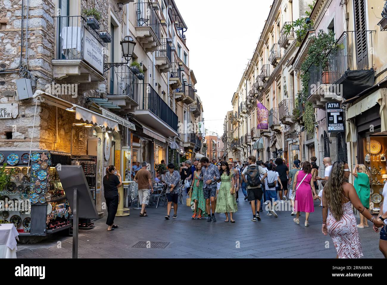 Giardini Naxos Sizilien Italien 08.07.2022 - Touristen, die am Nachmittag auf einer Gasse voller Menschen und Geschäfte spazieren gehen Stockfoto