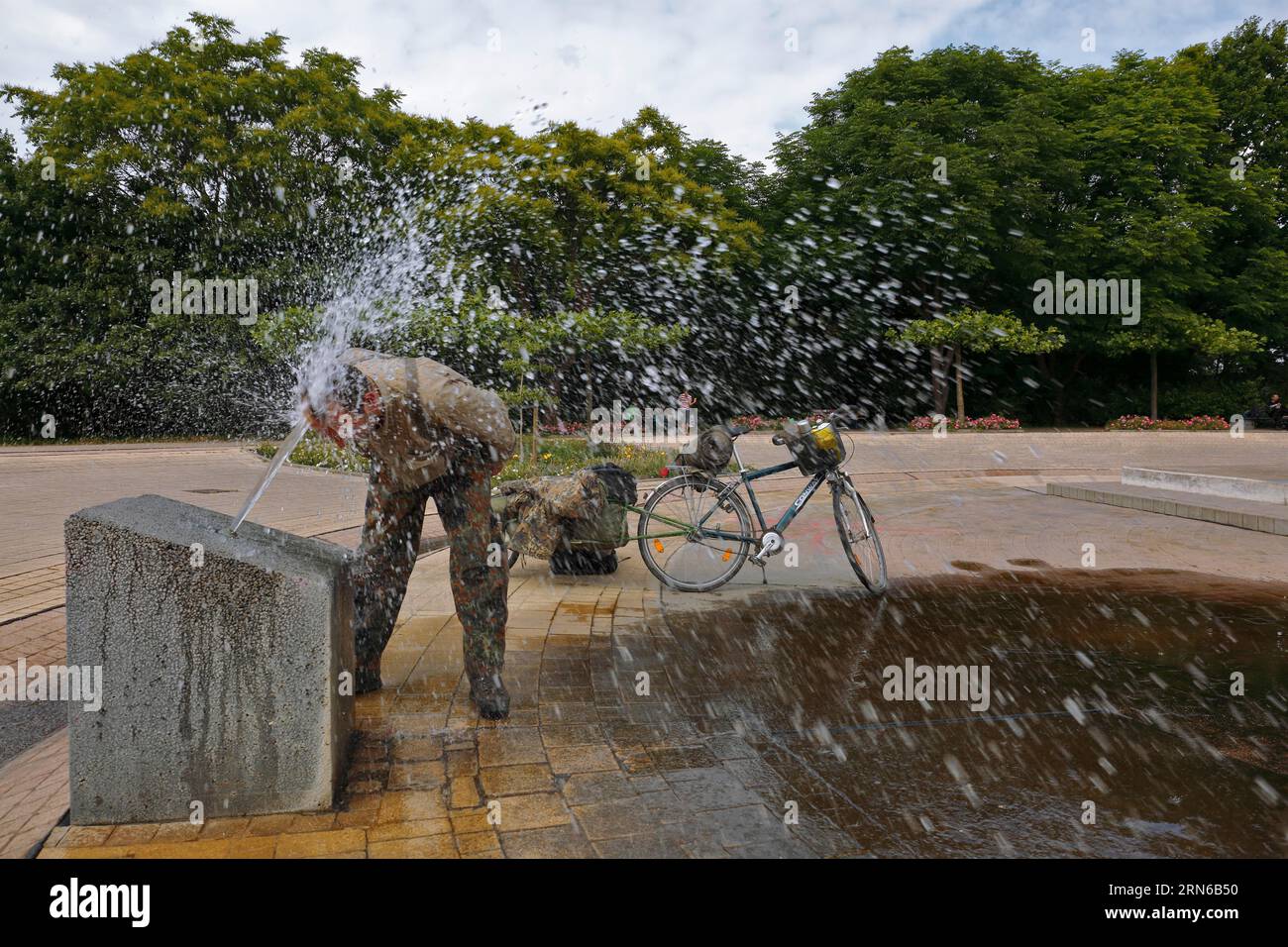 Radtourist erfrischt sich an einem öffentlichen Wasserspiel in Magdeburg, Sachsen-Anhalt, Deutschland Stockfoto