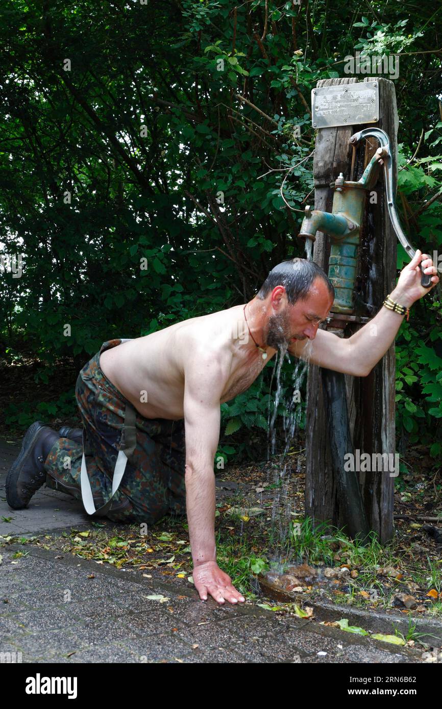 Radtourist erfrischt sich bei einer öffentlichen Pumpe in Magdeburg, Sachsen-Anhalt, Deutschland Stockfoto