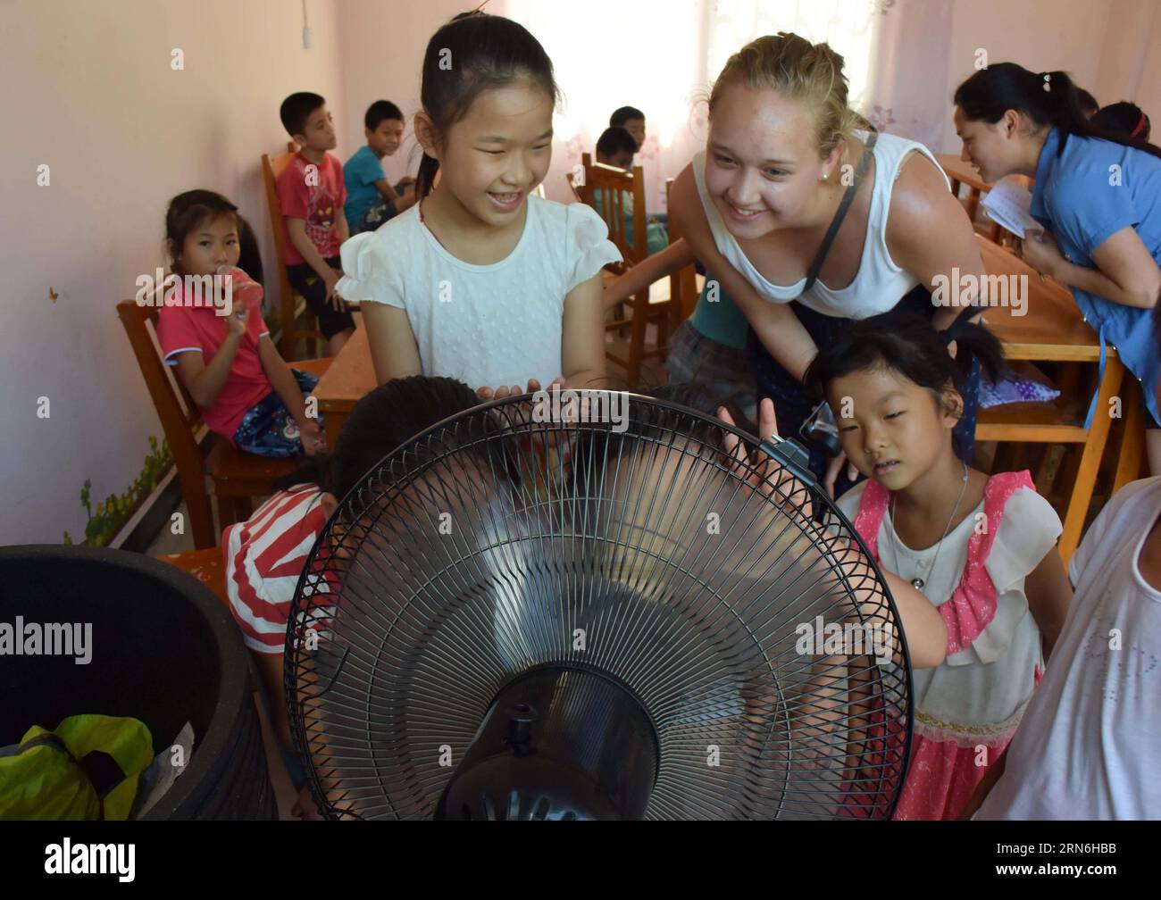 (150728) -- GONGCHENG , 28. Juli 2015 -- Josephine Meerman, eine niederländische Freiwillige von Greenway China, genießt die kühle Brise eines Elektroventilators mit Schulkindern im Dorf Langshan, Lianhua Stadt Gongcheng Yao Autonomous County, südwestchinesische autonome Region Guangxi, 28. Juli 2015. Laut Qin Liyan, Managing Director von Greenway China, einer gemeinnützigen Organisation zur Förderung des internationalen Bildungs- und Kulturaustauschs, nahmen seit 2008 jährlich 80 bis 100 Freiwillige überwiegend aus nordeuropäischen Ländern an Lehrprogrammen in Gongcheng Teil. ) (xcf) CHINA-GUANGX Stockfoto