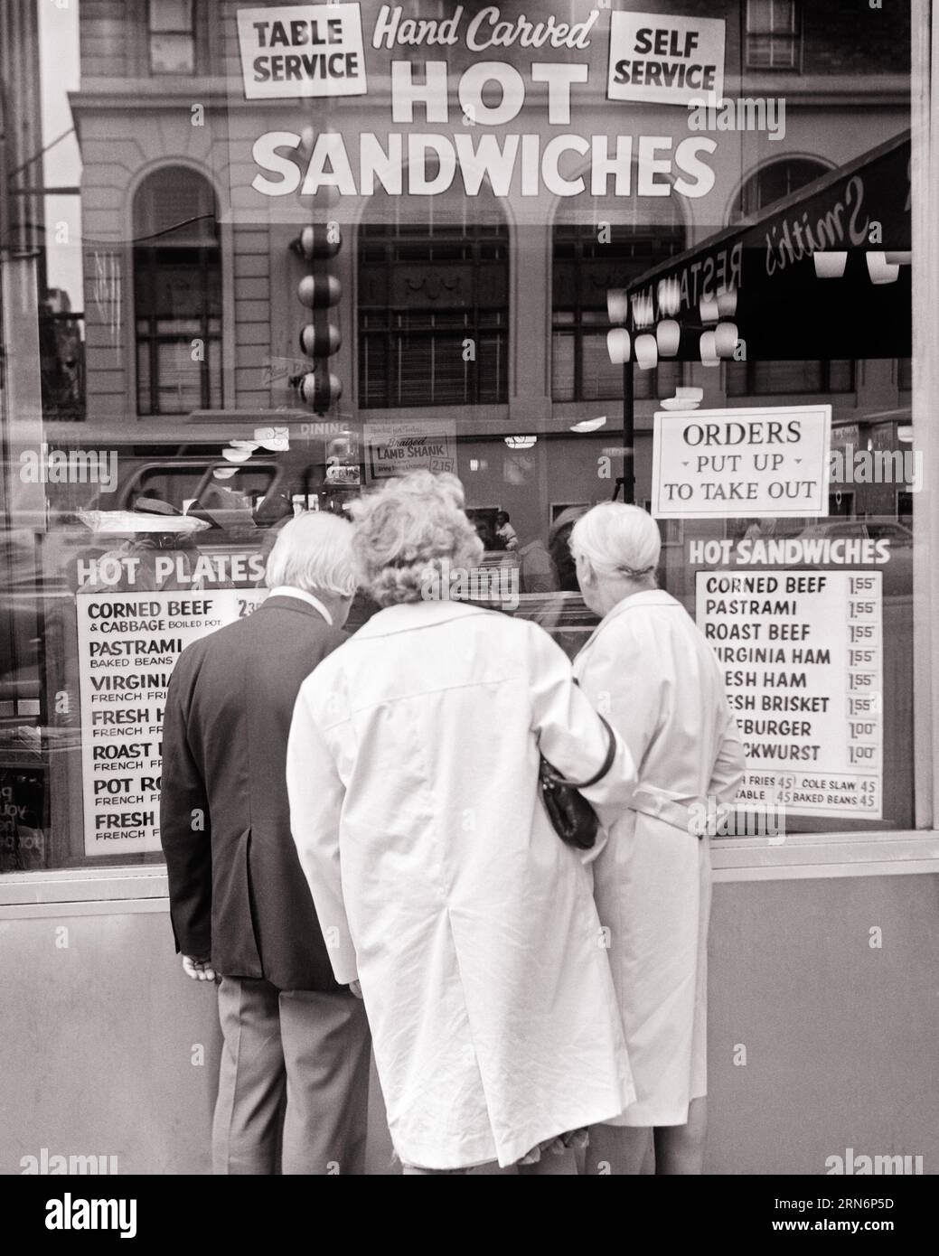 1970ER JAHRE DREI SENIOREN, DIE IN DAS FENSTER EINES DELIS SCHAUEN, UM HEISSE SPEISEN, SANDWICHES UND PLATTEN ZU BEWERBEN - F13354 HAR001 HARS FREUNDSCHAFT HALBE LÄNGE DAMEN PERSONEN INSPIRATION MÄNNER SENIOR MANN SENIOR ERWACHSENE SCHWARZWEISS TRAURIGKEIT SENIOR FRAU TRÄUMT ALTE OLDTIMER HOCHWINKEL OLDSTER ENTDECKUNG KUNDENSERVICE UND IN OPPORTUNITY TOURISTEN ÄLTERE KONZEPTIONELLE ERSCHWINGLICHE STÄDTE PREISE REFLEXIONEN PLATTEN ÄLTERE MANN ÄLTERE FRAU ZWEISAMKEIT SCHWARZ-WEISS-BÜRGER KOSTEN DELI HAR001 ALTMODISCH Stockfoto