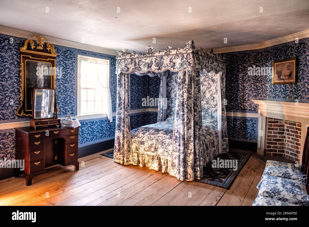 Mount Vernon Bedroom Alexandria VA // MOUNT VERNON, Alexandria, VA — der blaue Tapetenraum zeigt ein zeitgenössisches Dekor in einem der Schlafzimmer im Mount Vernon, dem historischen Anwesen von George Washington, dem ersten Präsidenten der Vereinigten Staaten. Dieses sorgfältig erhaltene Schlafzimmer spiegelt die Ästhetik und die Einrichtung wider, die typisch für amerikanische Häuser der oberen Klasse des späten 18. Jahrhunderts sind. Mount Vernon, der am Potomac River liegt, diente von 1754 bis zu seinem Tod 1799 als Wohnhaus Washingtons. Das Anwesen wird seit 1858 von der Mount Vernon Ladies’ Association verwaltet und gehört zu den Amerikanischen Staaten Stockfoto