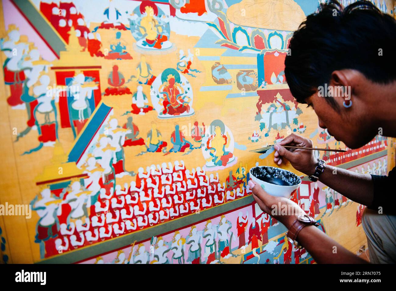 PEMA Wanza zieht Thangka in Lhasa an, der Hauptstadt der autonomen Region Tibet im Südwesten Chinas, 8. August 2015. Thangka, Musik, Film. Man kann sich nie vorstellen, wie diese scheinbar irrelevanten Elemente zusammenkommen, bis man die 21-jährige Pema Wanza trifft. Thangka, ein tibetisches Rollbanner, das verschiedene Arten von Inhalten darstellt, ist in jedem Klosterfamilienhaus in der Autonomen Region Tibet zu sehen und ist in den letzten Jahren zu einer wertvollen Sammlung geworden. Wanza begann mit elf Jahren Thangka zu zeichnen. Nach dem Abschluss der Grundschule entschied er sich, Thangka-Zeichnung als seinen Beruf und wir zu machen Stockfoto