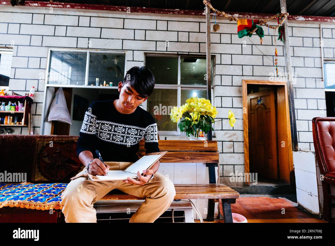 PEMA Wanza schreibt Texte für seine neuen Songs nach der Arbeit in Lhasa, der Hauptstadt der autonomen Region Tibet im Südwesten Chinas, 8. August 2015. Thangka, Musik, Film. Man kann sich nie vorstellen, wie diese scheinbar irrelevanten Elemente zusammenkommen, bis man die 21-jährige Pema Wanza trifft. Thangka, ein tibetisches Rollbanner, das verschiedene Arten von Inhalten darstellt, ist in jedem Klosterfamilienhaus in der Autonomen Region Tibet zu sehen und ist in den letzten Jahren zu einer wertvollen Sammlung geworden. Wanza begann mit elf Jahren Thangka zu zeichnen. Nach dem Abschluss der Grundschule entschied er sich, Thangka dra zu machen Stockfoto
