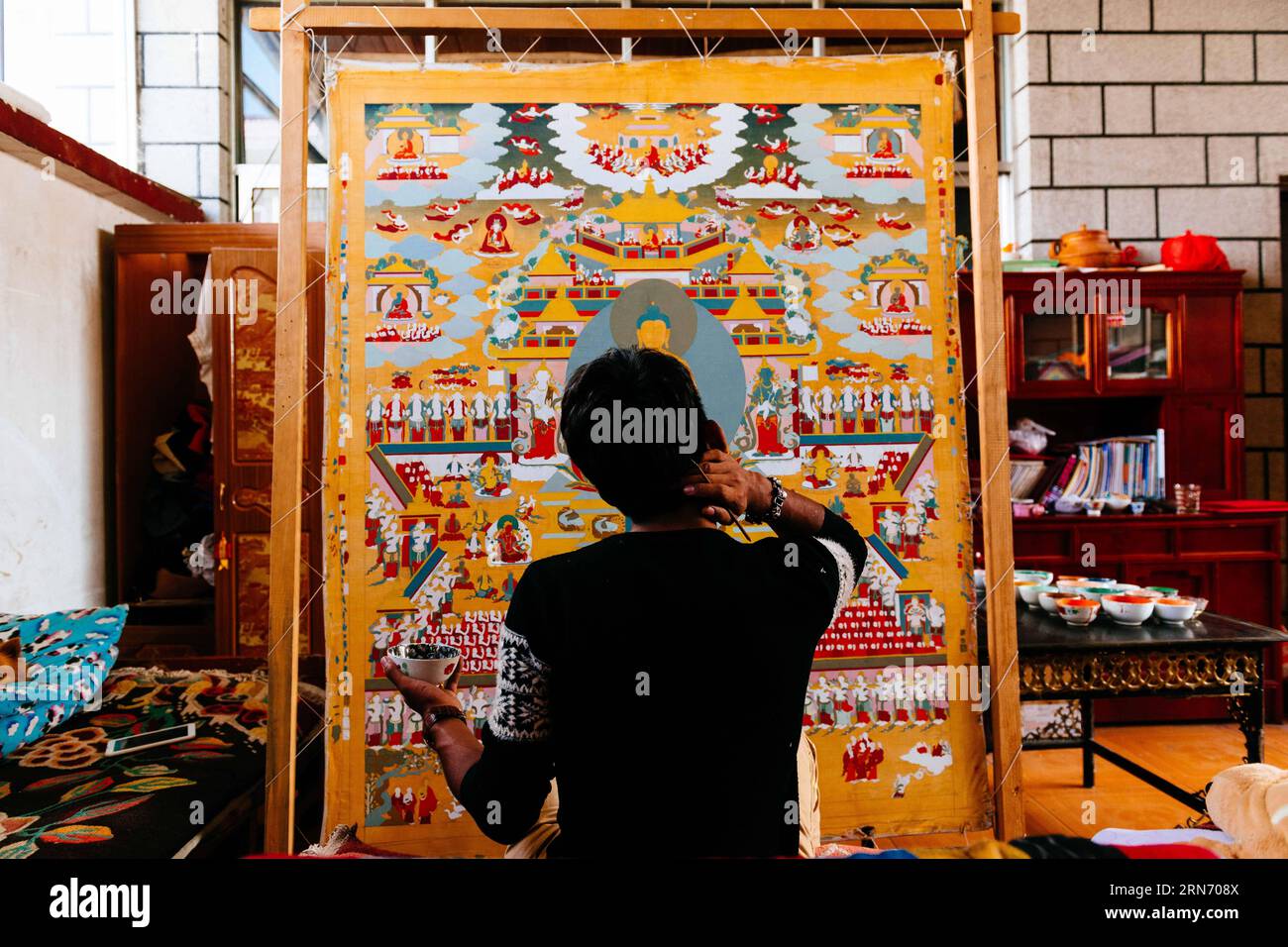 PEMA Wanza streckt sich beim Thangka-Malen in Lhasa, der Hauptstadt der autonomen Region Tibet im Südwesten Chinas, am 8. August 2015. Thangka, Musik, Film. Man kann sich nie vorstellen, wie diese scheinbar irrelevanten Elemente zusammenkommen, bis man die 21-jährige Pema Wanza trifft. Thangka, ein tibetisches Rollbanner, das verschiedene Arten von Inhalten darstellt, ist in jedem Klosterfamilienhaus in der Autonomen Region Tibet zu sehen und ist in den letzten Jahren zu einer wertvollen Sammlung geworden. Wanza begann mit elf Jahren Thangka zu zeichnen. Nach dem Abschluss der Grundschule entschied er sich, Thangka-Drawi zu machen Stockfoto