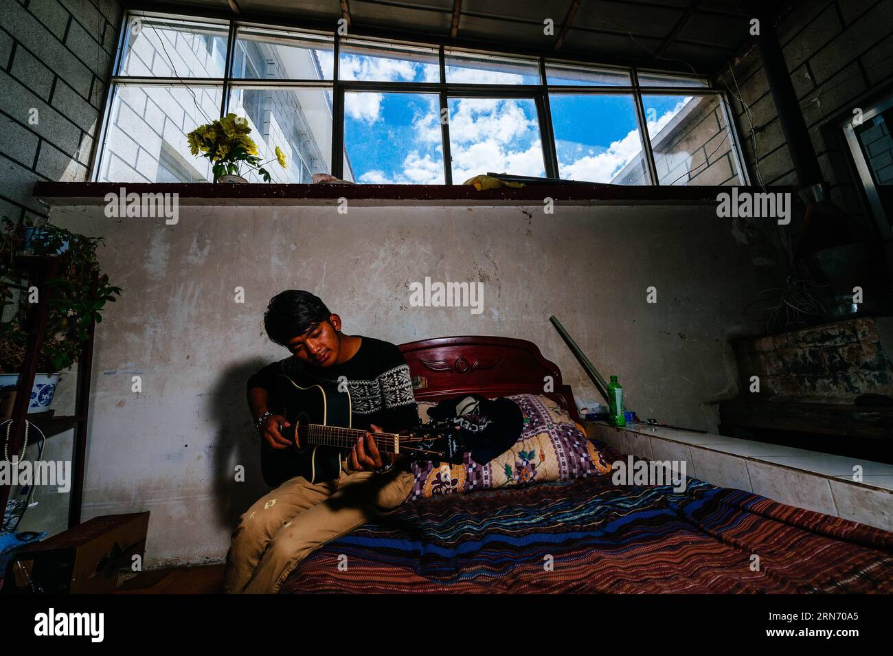 PEMA Wanza spielt die Gitarre, um in Lhasa, der Hauptstadt der autonomen Region Tibet im Südwesten Chinas, am 8. August 2015 zu entspannen. Thangka, Musik, Film. Man kann sich nie vorstellen, wie diese scheinbar irrelevanten Elemente zusammenkommen, bis man die 21-jährige Pema Wanza trifft. Thangka, ein tibetisches Rollbanner, das verschiedene Arten von Inhalten darstellt, ist in jedem Klosterfamilienhaus in der Autonomen Region Tibet zu sehen und ist in den letzten Jahren zu einer wertvollen Sammlung geworden. Wanza begann mit elf Jahren Thangka zu zeichnen. Nach dem Abschluss der Grundschule entschied er sich, Thangka-Zeichnung als sein Prof zu machen Stockfoto
