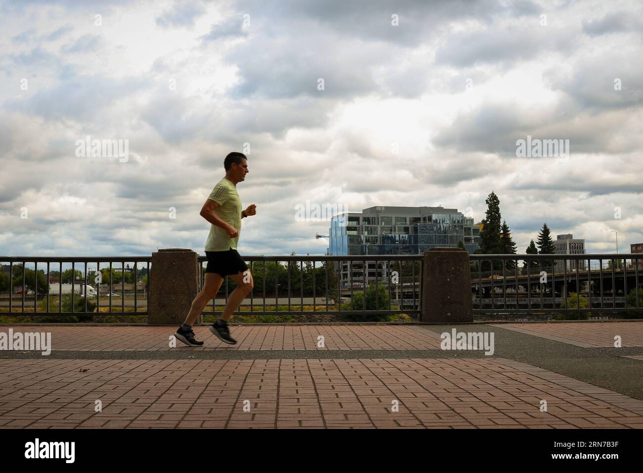 Ein Mann, der am Willamette River im Tom McCall Waterfront Park in der Innenstadt von Portland, Oregon, entlang läuft Stockfoto