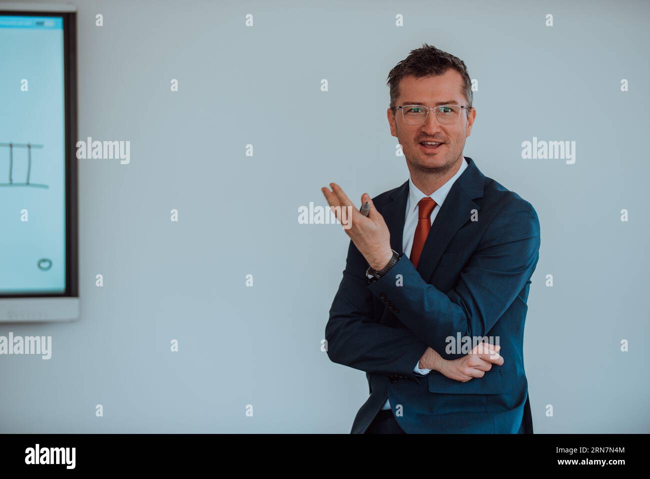 Ein modern gekleideter Professor vermittelt Studenten, die aufmerksam zuhören, und schafft eine dynamische Szene des Wissensaustauschs und fokussierten Lernens Stockfoto