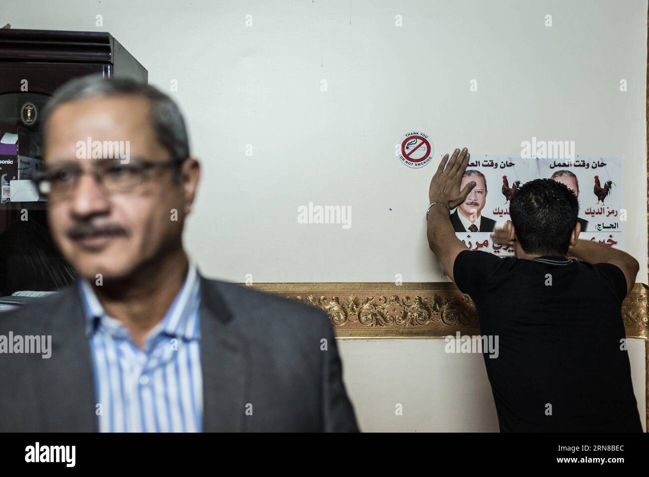 (151015) -- MINYA, 15. Oktober 2015 -- ein Assistent von Khairy Marzouk (L), einem unabhängigen Kandidaten für die anstehenden parlamentswahlen, bringt am 15. Oktober 2015 Poster an der Wand seines Büros im Stadtzentrum von El-Minya, Ägypten, auf. Die lang erwarteten Parlamentswahlen in Ägypten werden in zwei Phasen durchgeführt, die sich auf die 27 Provinzen des Landes erstrecken. Die erste Phase, die 14 Provinzen umfasst, findet am 18. Und 19. Oktober statt, die zweite Phase, die die übrigen 13 Provinzen am 22. Und 23. November umfasst. ) ÄGYPTEN-MINYA-PARLAMENT-WAHL PanxChaoyue PUBLICATIONxNOTxINxCHN Minya OKT 15 2015 zum Assistenten von Khairy Marzo Stockfoto