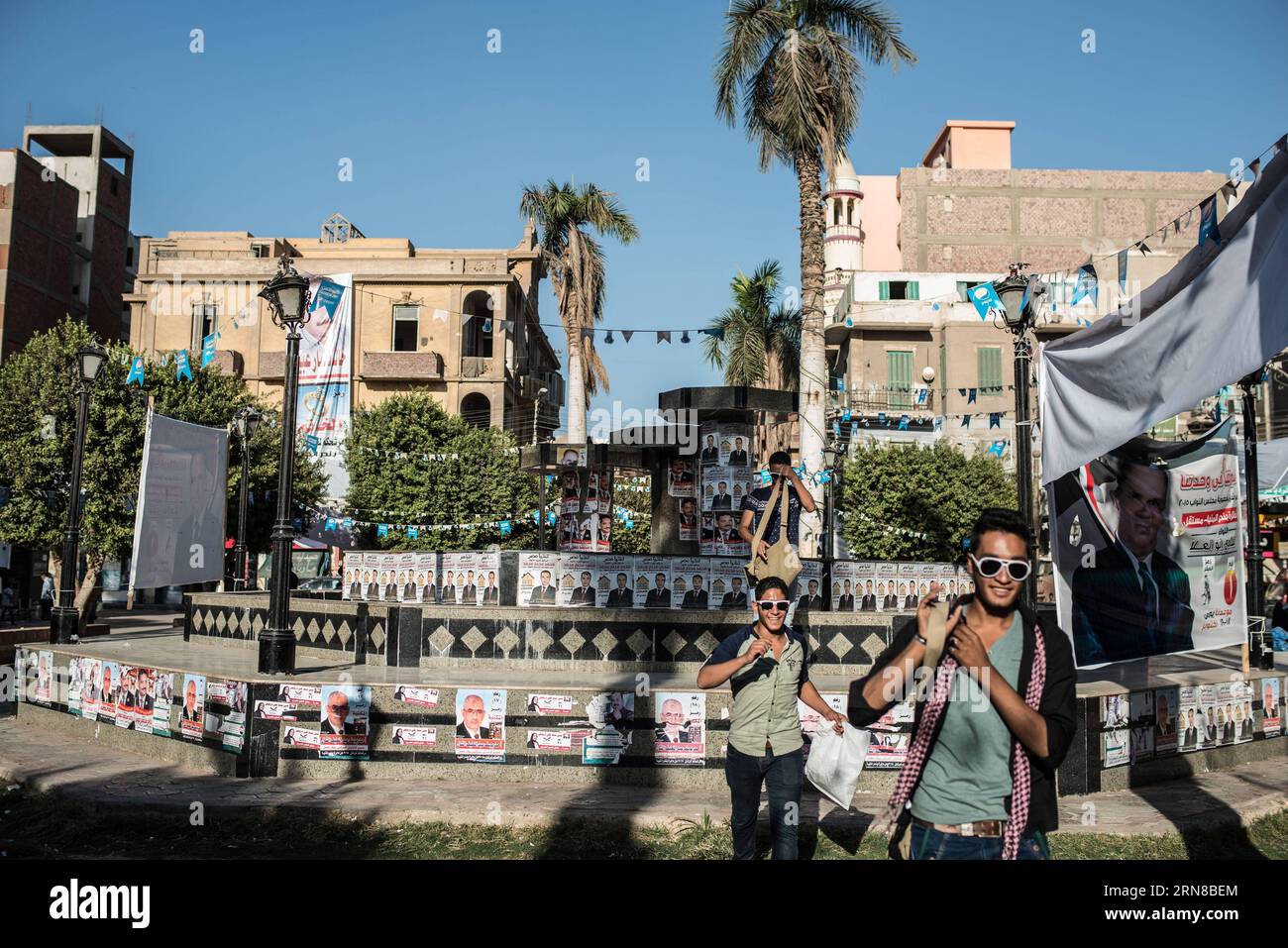 (151015) -- MINYA, 15. Oktober 2015 -- Ägypter gehen am Palastplatz vorbei, voller Plakate von Kandidaten für die anstehenden Parlamentswahlen im Stadtzentrum von El-Minya, Ägypten, am 15. Oktober 2015. Die lang erwarteten Parlamentswahlen in Ägypten werden in zwei Phasen durchgeführt, die sich auf die 27 Provinzen des Landes erstrecken. Die erste Phase, die 14 Provinzen umfasst, findet am 18. Und 19. Oktober statt, die zweite Phase, die die übrigen 13 Provinzen am 22. Und 23. November umfasst. ) ÄGYPTEN-MINYA-PARLAMENT-WAHL PanxChaoyue PUBLICATIONxNOTxINxCHN Minya OCT 15 2015 Ägypter gehen am Palastplatz vorbei voller Plakate von Candida Stockfoto