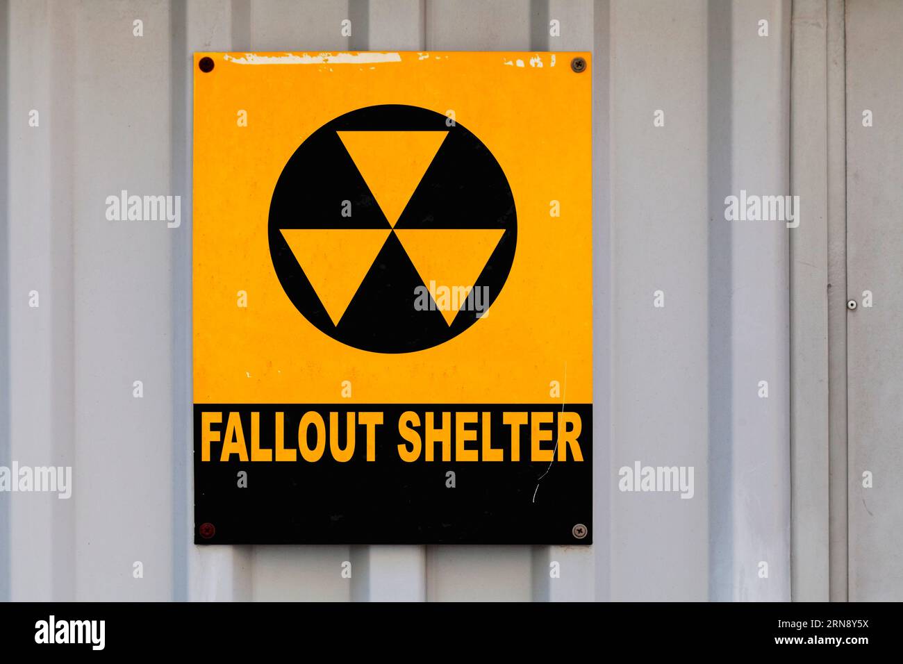 Schwarzes nukleares Symbol auf einem gelben Schild mit der Aufschrift „Fallout Shelter“. Stockfoto