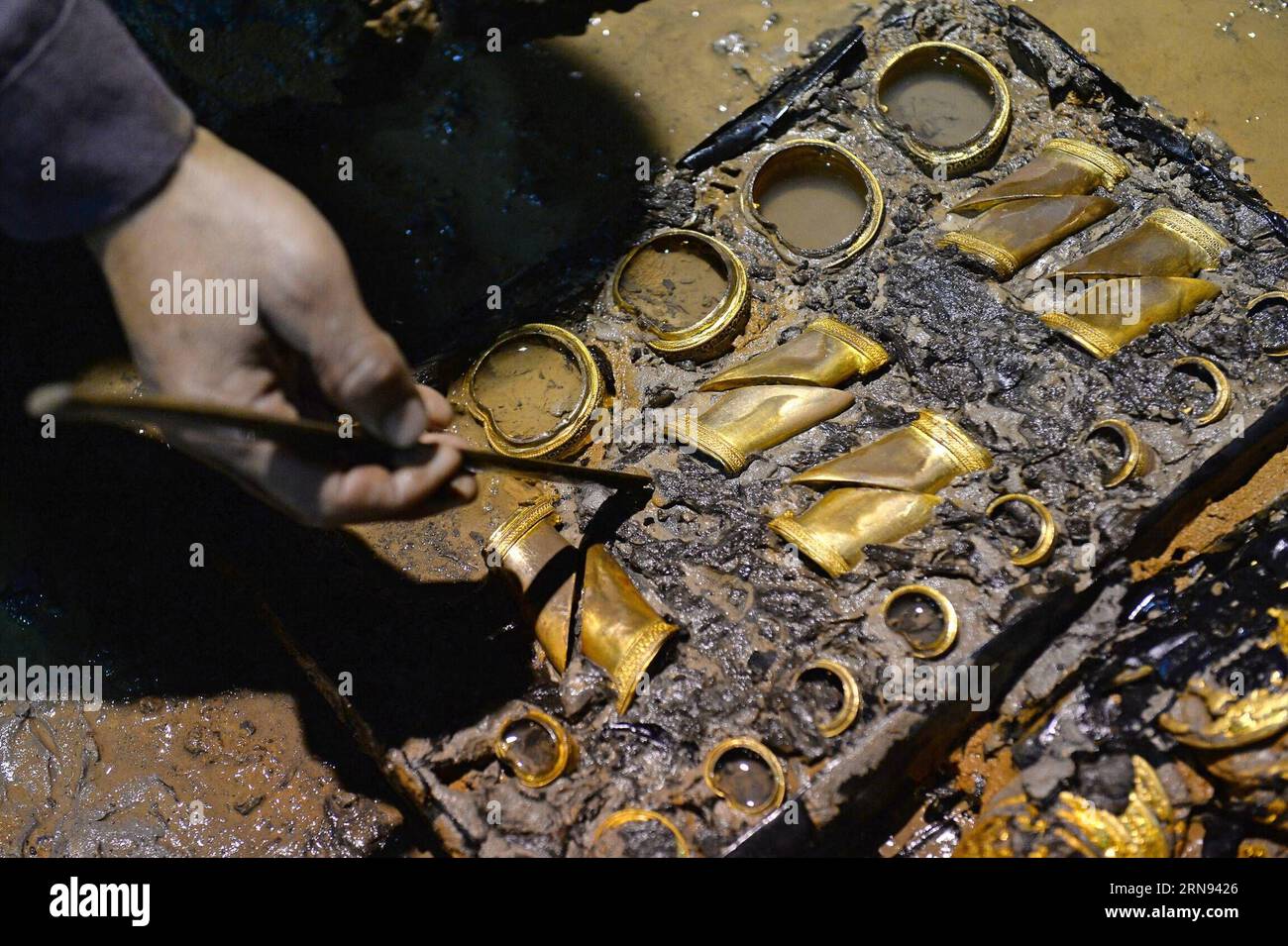 (151117) -- NANCHANG, 17. November 2015 -- ein Archäologe reinigt die hufförmigen Ingots in einem aristokratischen Grab, das aus der westlichen Han-Dynastie (206 v. Chr. - 24 n. Chr.) stammt, in Nanchang, der Hauptstadt der ostchinesischen Provinz Jiangxi, 17. November 2015. Chinesische Archäologen entdeckten am Dienstag 75 Goldmünzen und hufförmige Ingots im Grab. Die Goldobjekte -- 25 Goldhufe und 50 sehr große Goldmünzen -- sind die größte Einzelmenge von Goldgegenständen, die jemals in einem Grab der Han-Dynastie gefunden wurden. ) (zhs) CHINA-NANCHANG-ARCHAEOLOGY (CN) WanxXiang PUBLICATIONxNOTxINxCHN Nanchang Nov 17 2015 to ARCHAEOLOGIST Cleans T Stockfoto