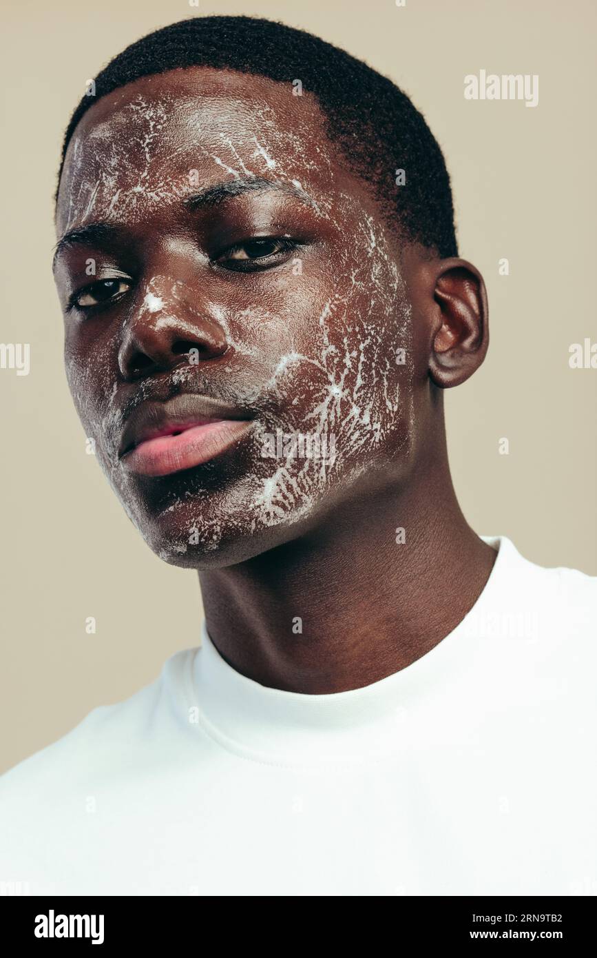 Mann, der eine gesunde Hautpflege-Routine für seine Melaninhaut praktiziert und sein Gesicht mit einem feuchtigkeitsspendenden Gesichtswasser reinigt. Junger schwarzer Mann, der einen Gesichtsreiniger benutzt Stockfoto