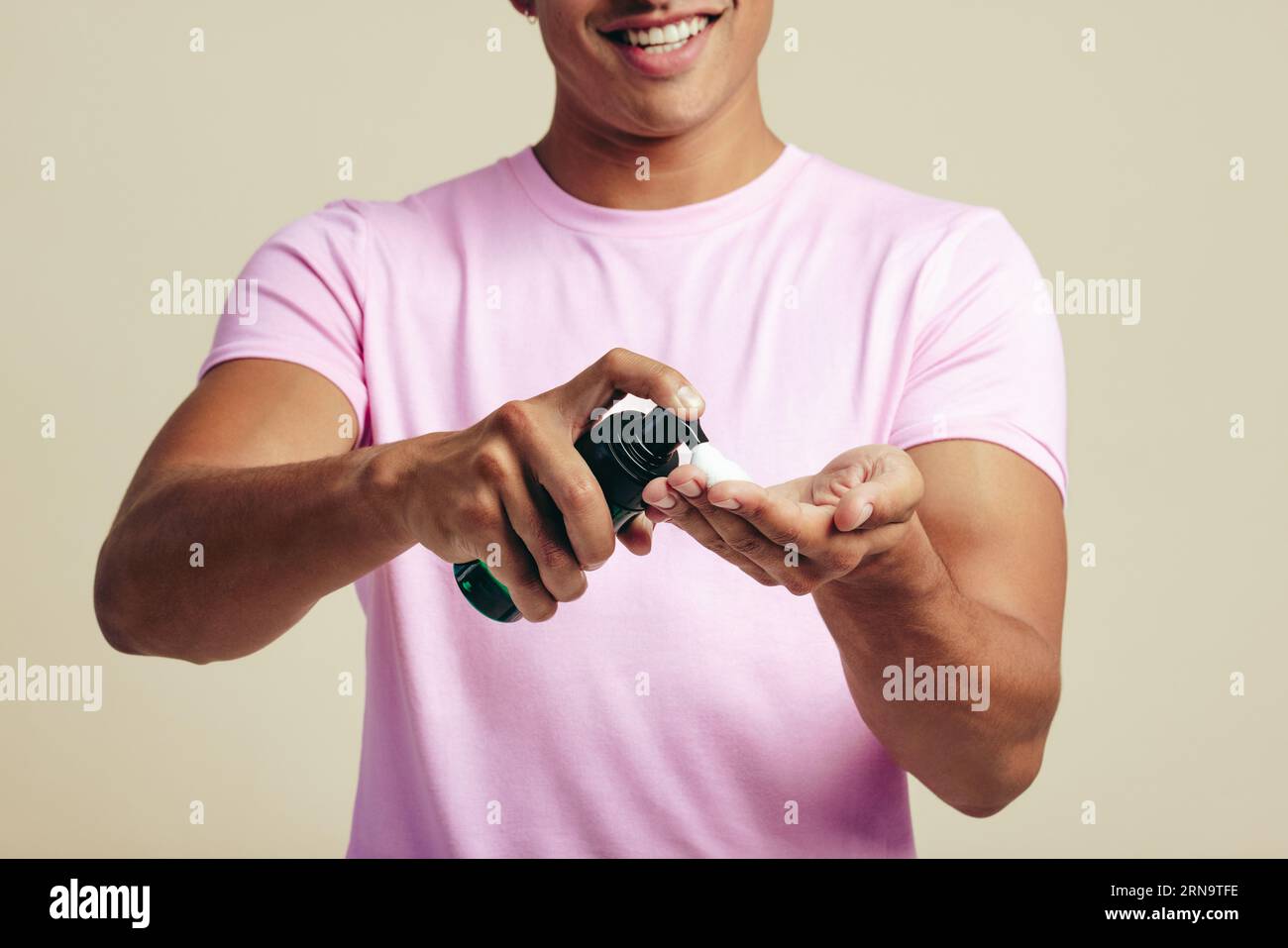 Der Mann reinigt seine Hände mit Gesichtswasser und bereitet sich auf eine gründliche und erfrischende Reinigung vor. Gutaussehender junger Mann verwöhnt seine Haut, um sie sauber und gesund zu halten Stockfoto