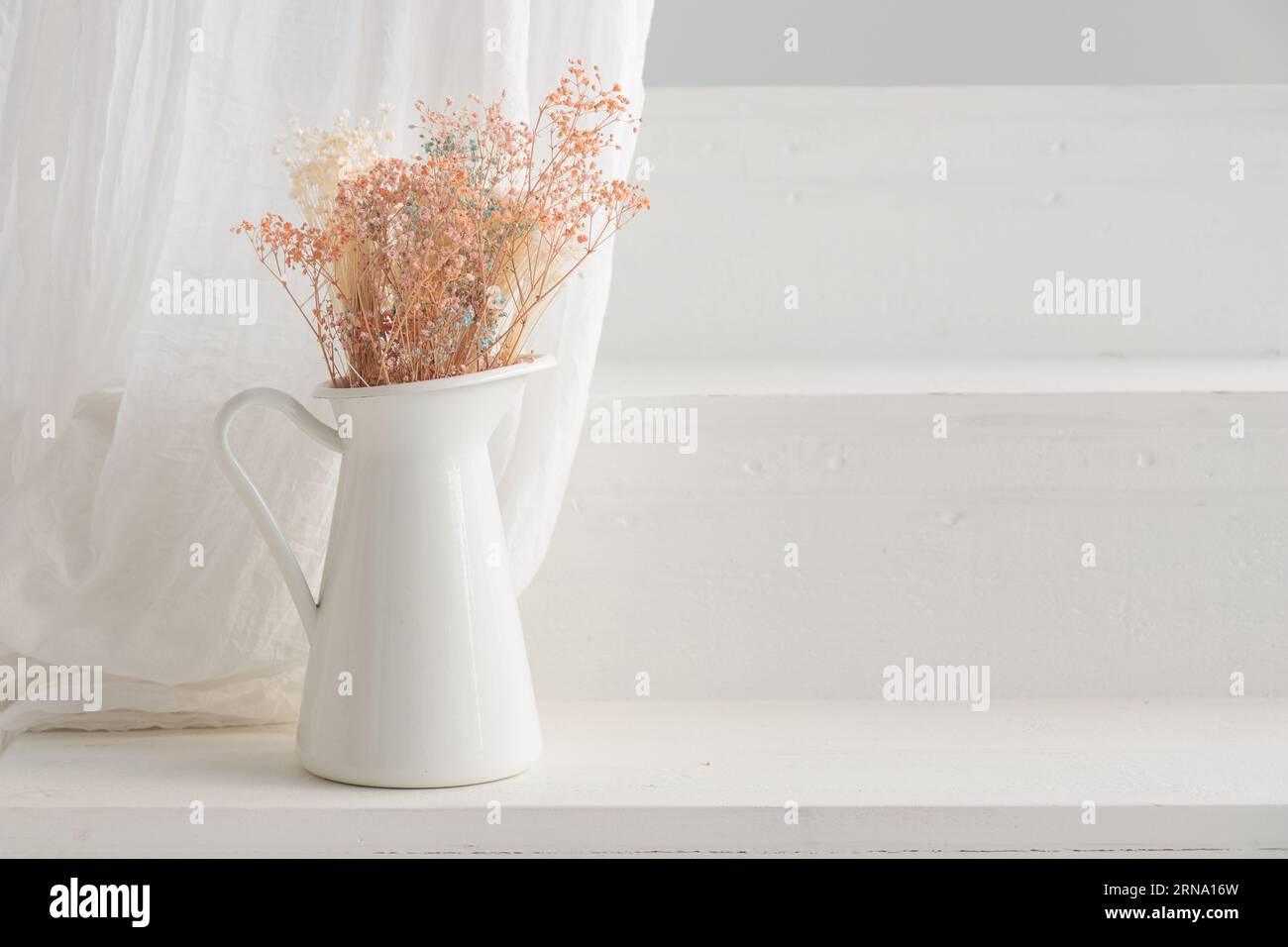 Trockene Blumen in weißer Vase auf der Veranda von whitehouse. Minimalistische Stillzeit Stockfoto