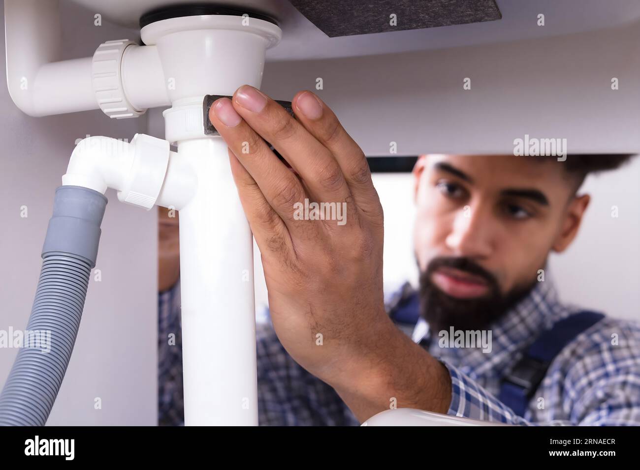 Nahaufnahme eines männlichen Klempner zur Festsetzung Waschbecken Rohr in der Küche Stockfoto