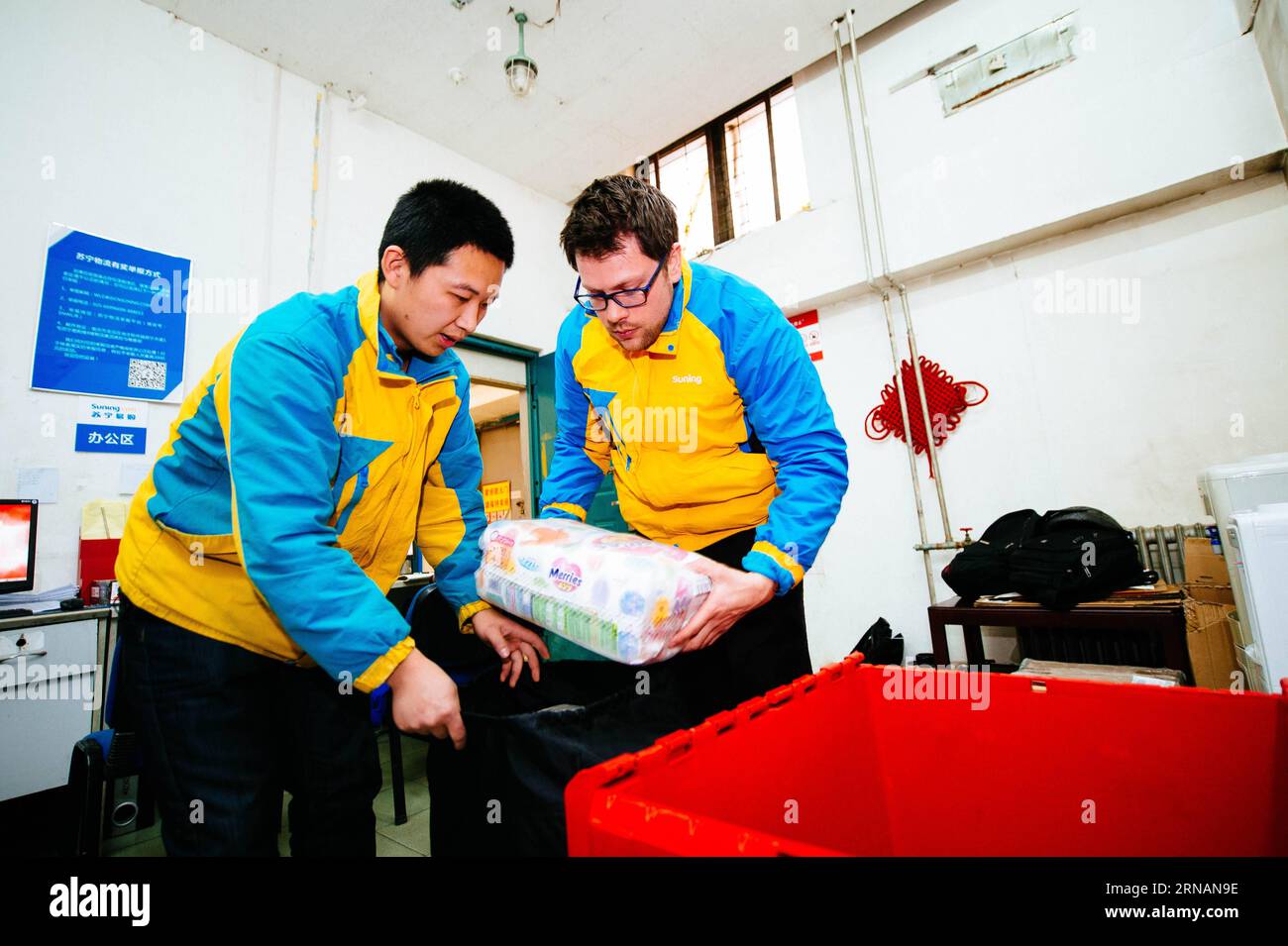 Die Suning-Kuriere Li Yunwang (L) und Frank Hersey steckten am 1. Februar 2016 in Peking, der Hauptstadt Chinas, Ladungen in einen Rucksack. Frank Hersey, ein 33-jähriger Brite, der in Peking für ein Magazin arbeitet, ist heute als Teilzeitkurier bei Suning, einem chinesischen E-Commerce-Unternehmen, beschäftigt. Während das Frühlingsfest näher rückt, ist Suning kühn, ausländische Kuriere einzuschreiben, um den Personalmangel in dieser Zeit auszugleichen. Allerdings ist es in China ungewöhnlich, dass ein Ausländer Pakete liefert, da von Ausländern hier immer erwartet wird, dass sie anständige Arbeitsplätze annehmen. Frank Hersey, der sich mit Orientalismus in Großbritannien beschäftigt und sprechen kann Stockfoto