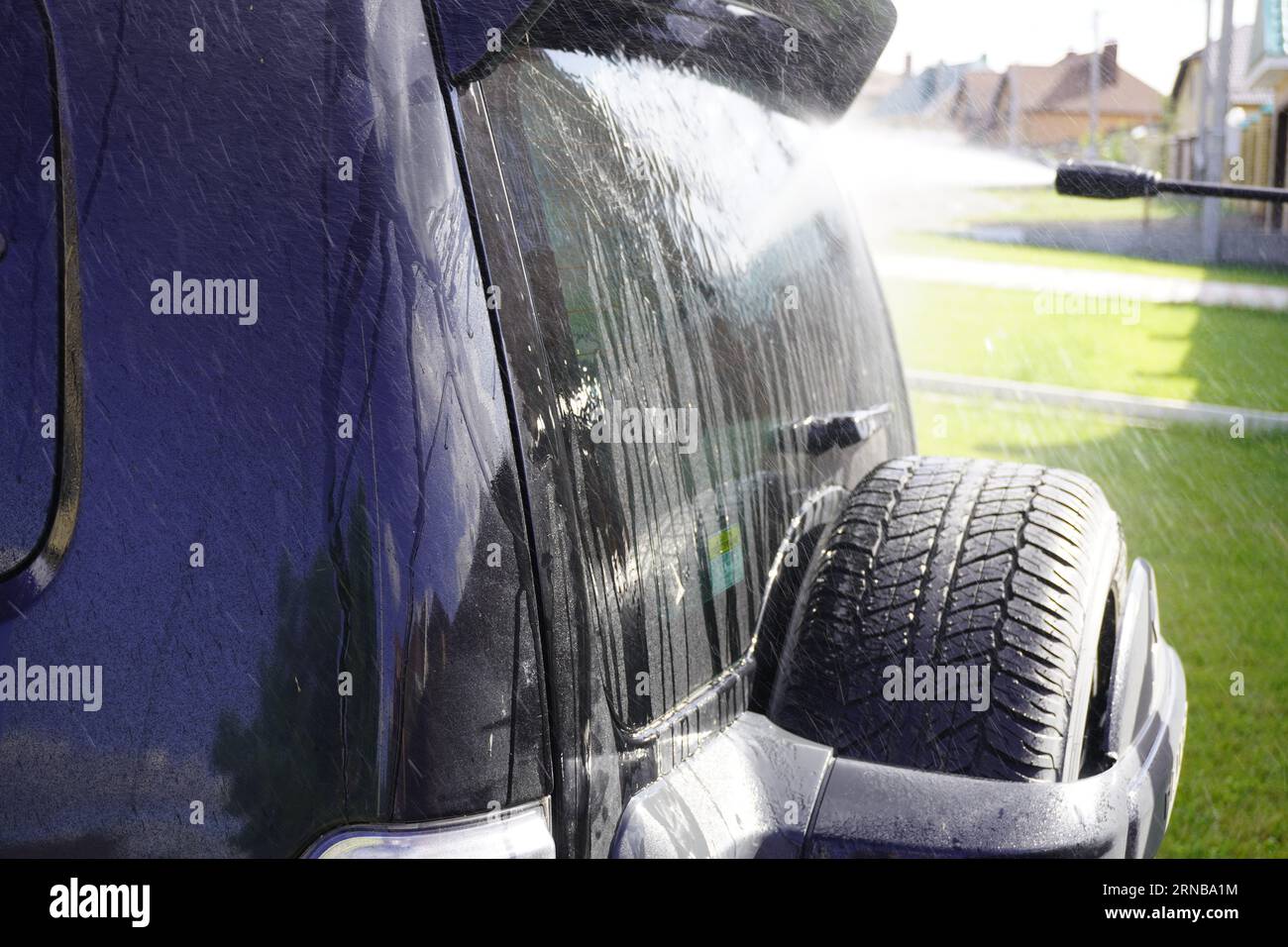 Man wäscht Auto mit Autowaschanlage - Hochdruckreiniger, Shampoo, Schwämme und Mikrofaser-Handtücher Stockfoto