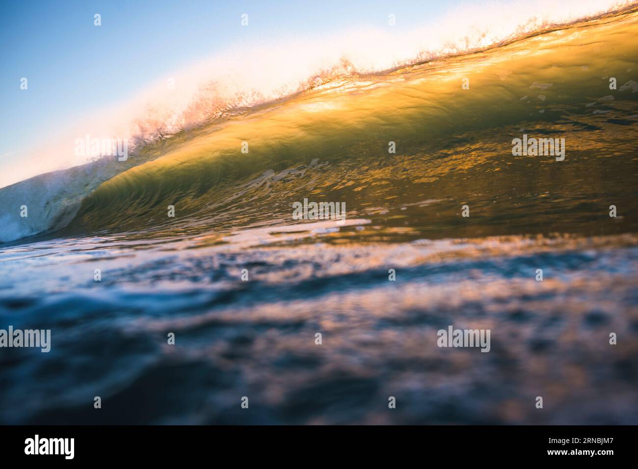 Hinterleuchtete Ozeanwelle bei Sonnenaufgang Stockfoto