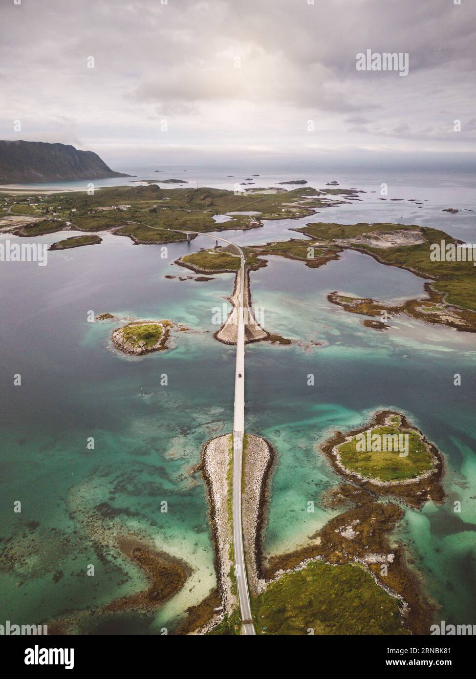 Auto überquert eine Brücke auf den Lofoten-Inseln an einem bewölkten Tag Stockfoto